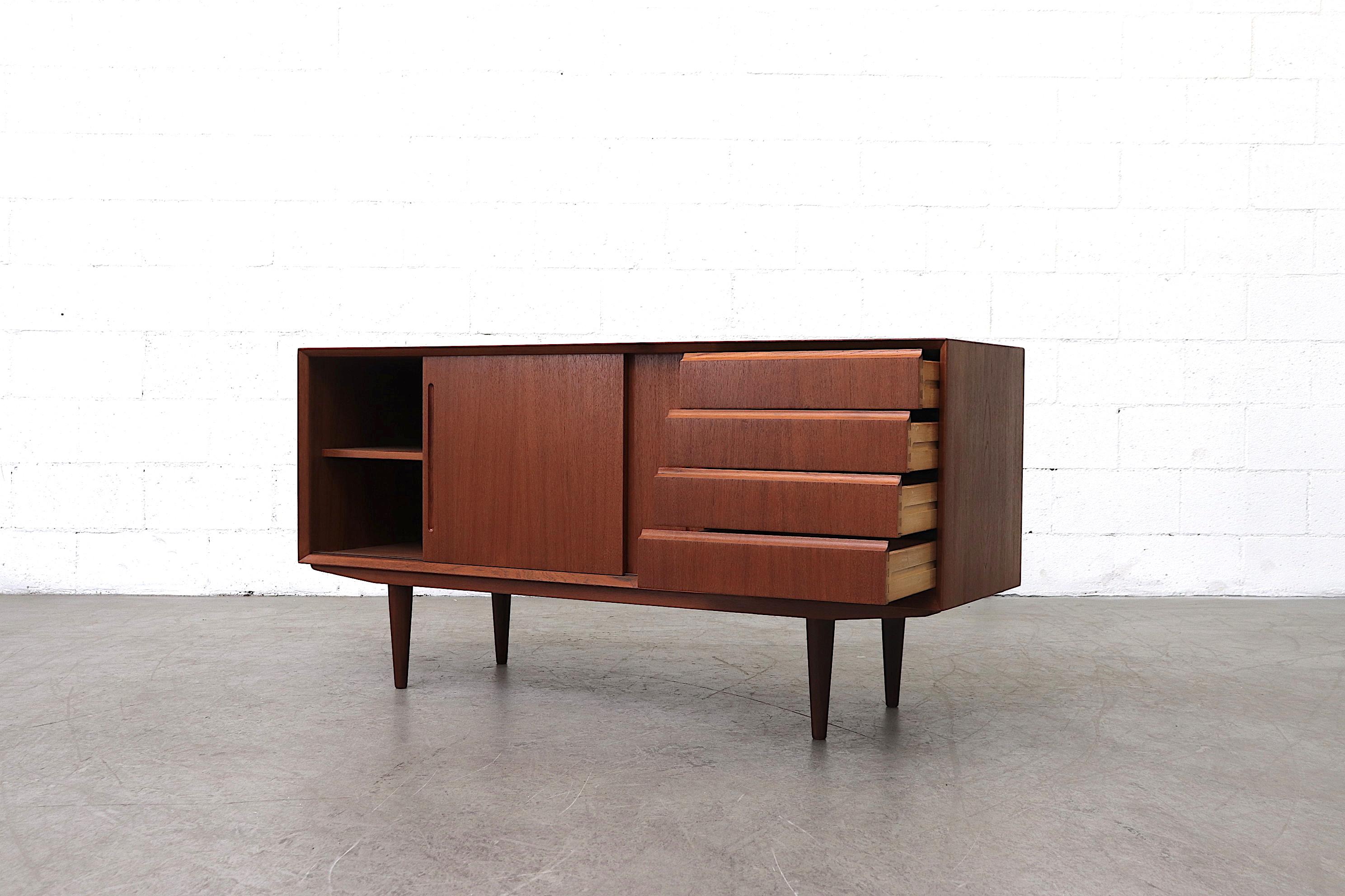 Handsome midcentury teak credenza with side stacked drawers and double sliding doors. Top drawer felt lined with slight staining. In good original condition with wear consistent with its age and use.