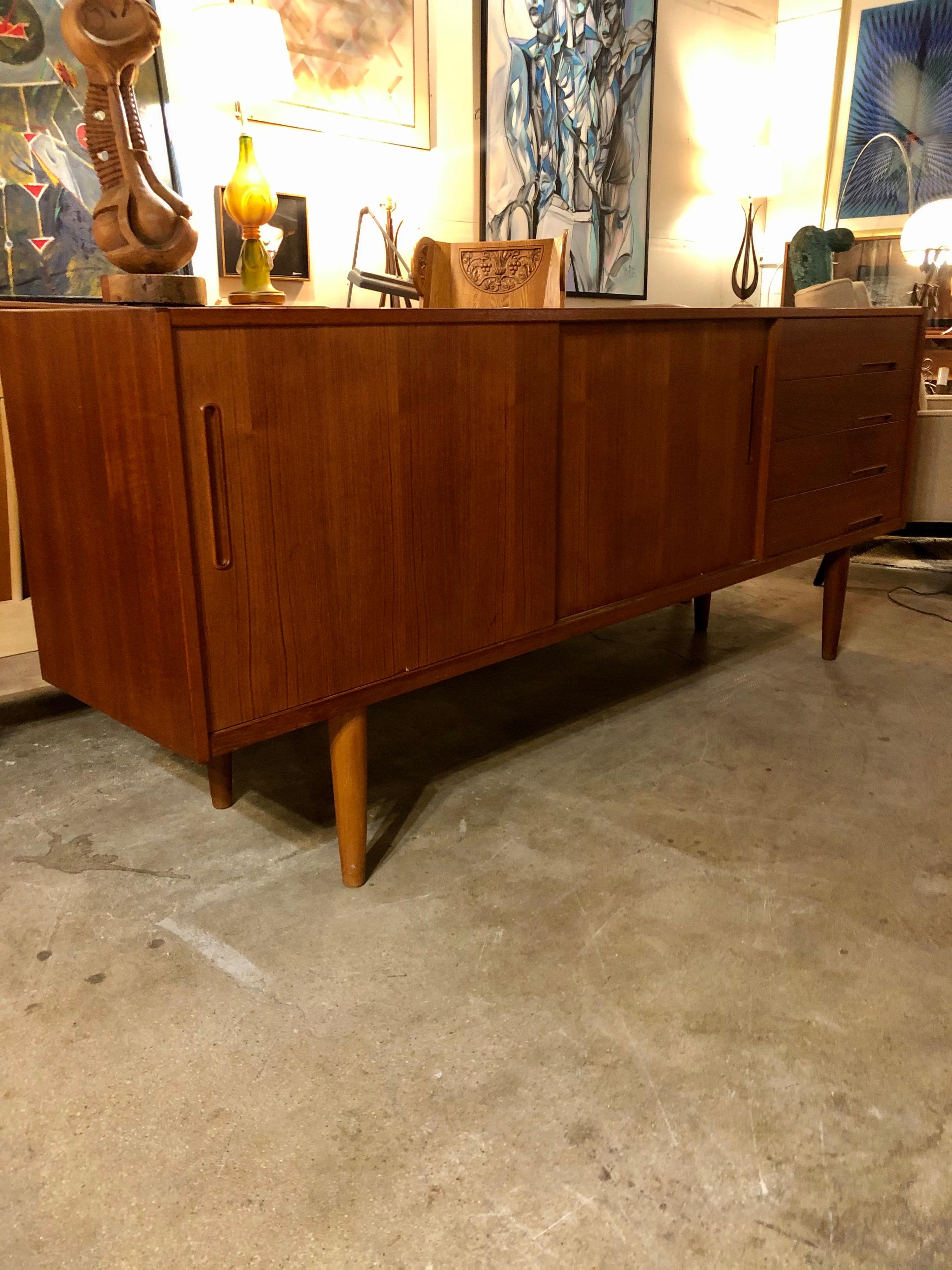 Mid-century teak credenza from the 60s was designed by Nils Jonsson for Hugo Troed features four drawers one with cutlery sections in blue felt and two sliding drawers. This modern credenza is in good condition.