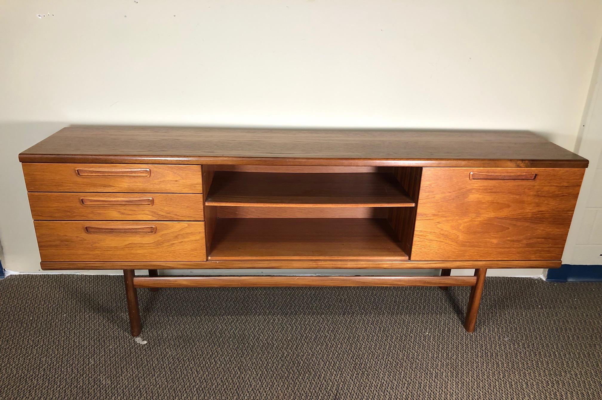 Beautiful teak credenza with drawers and drop down cabinet. Used to have glass doors in the middle that are missing.
Gorgeous sculpted teak handles. 
Very good condition overall. Very nice front. Some scratches and stains on the top as shown in