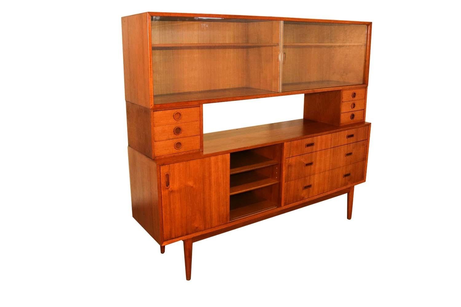 Simply perfect Danish teak credenza by Lyby Mobler, made in Denmark. A two-sided Mid-Century Modern teak credenza with carved teak pulls. This stylish modern room divider features rich teak patina, carved teak pulls with unique open and closed