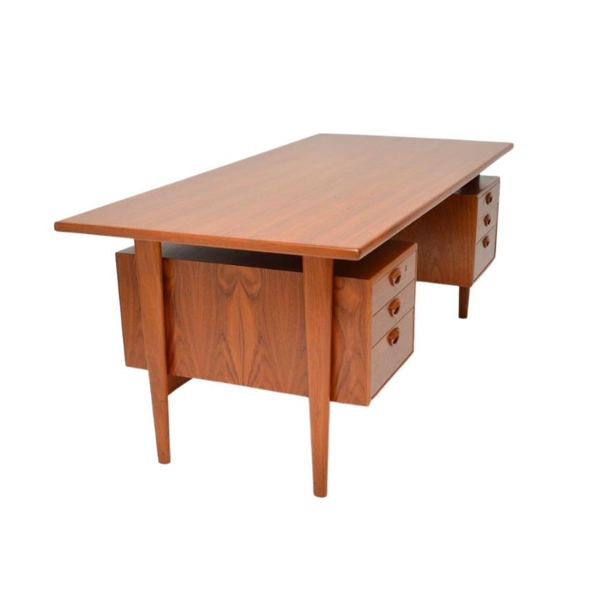 A large and impressive vintage Danish desk in teak. Designed by Kai Kristiansen, it dates from the 1960’’s. The back features two lockable compartments and an open shelf. 

A practical piece, this desk features three drawers on either side for