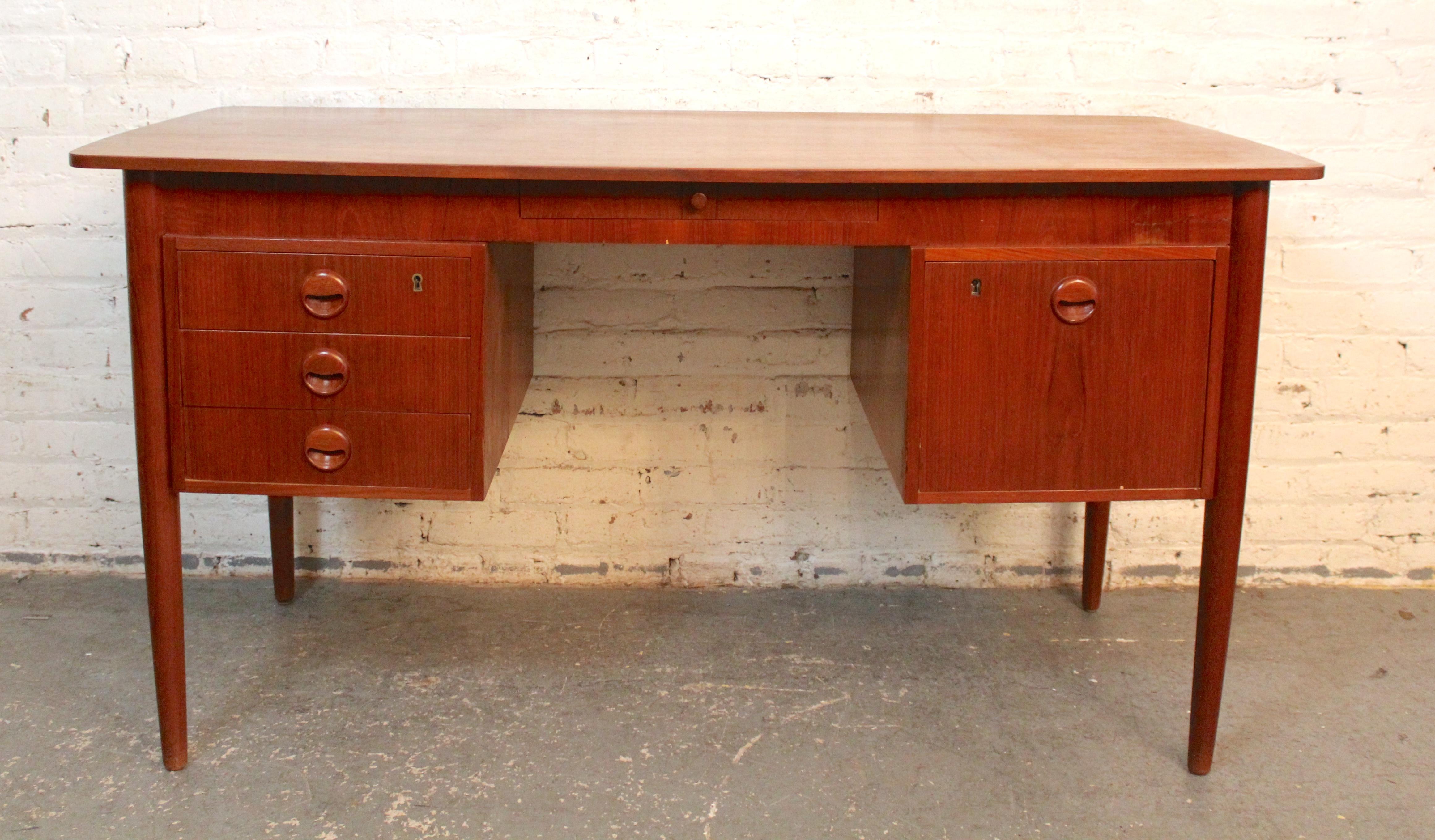 Mid-century modern Danish style teak desk with finished back. Featuring five drawers with sculpted teak handles, long tapered legs, and rich teak grain throughout.
Please confirm location with dealer NY or NJ