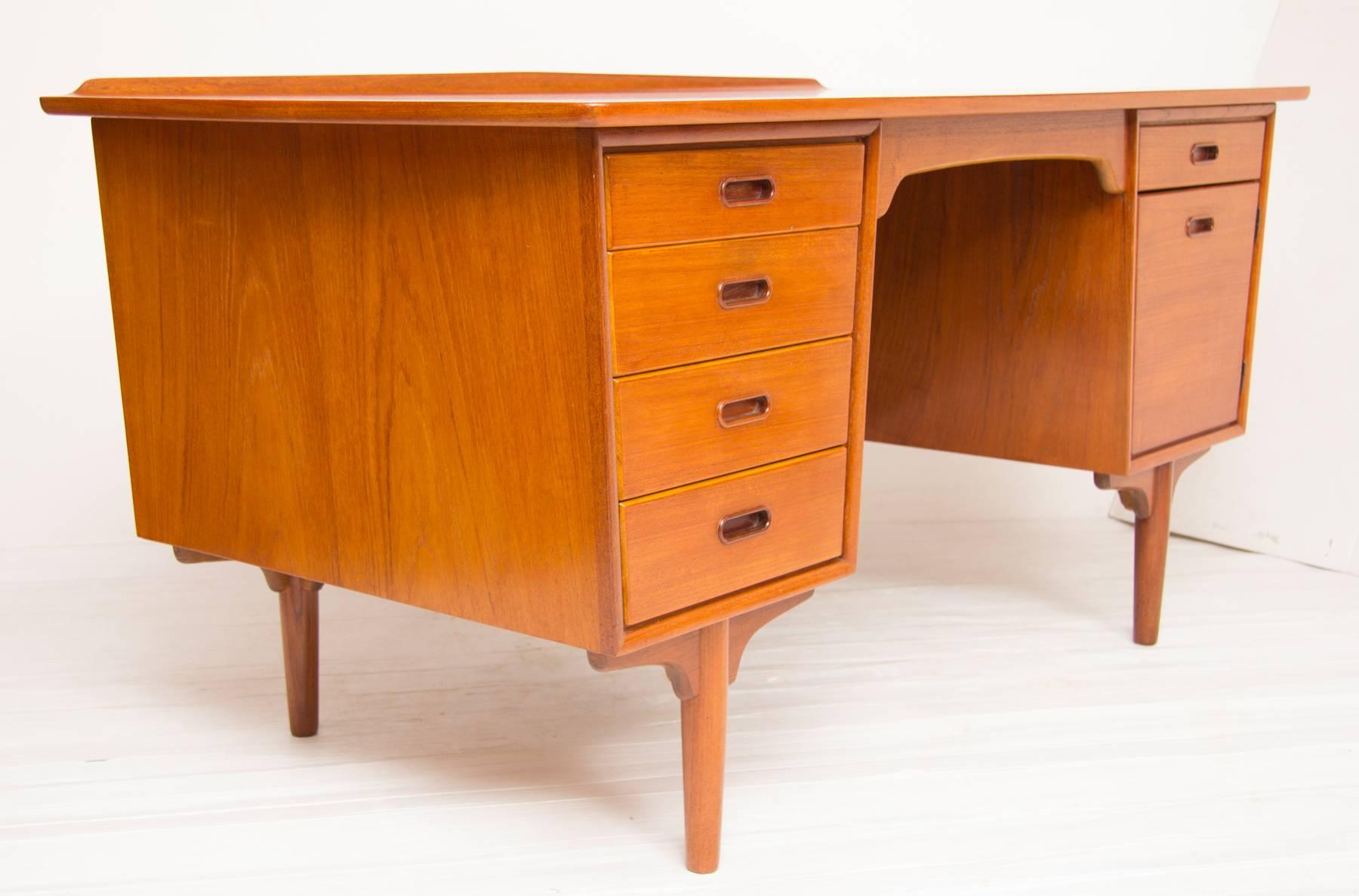 1960s teak desk with four drawers to the left and a door with drawer above to the right. To the rear there is a full length book shelf.