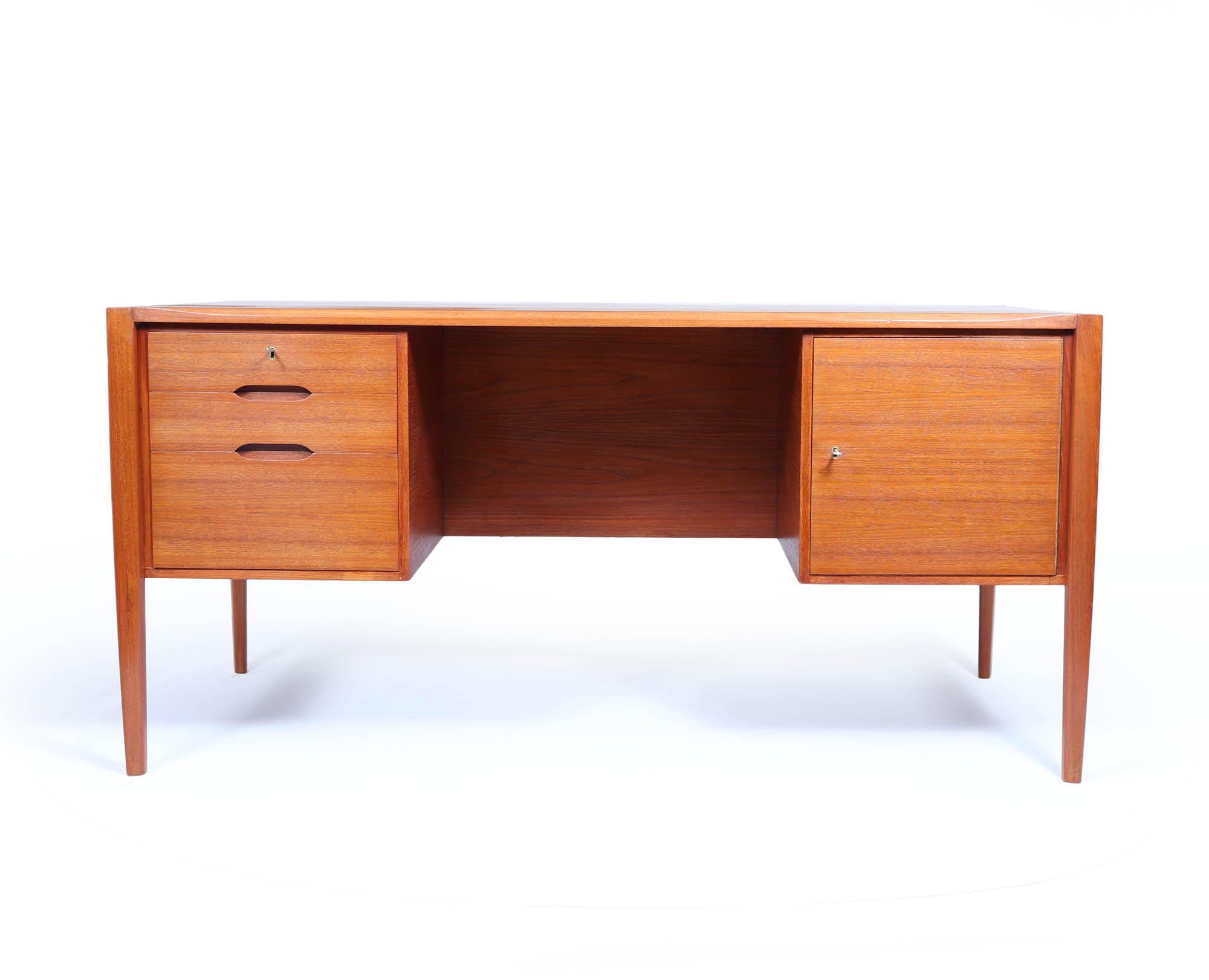 Mid Century Teak Desk 
A lovely quality desk produced in the 1960’s by Wilhelm Renz in Germany, the desk as three drawers to the left top one being lockable and a cupboard with a slide to the right, the shaped legs and chamfered top make this desk