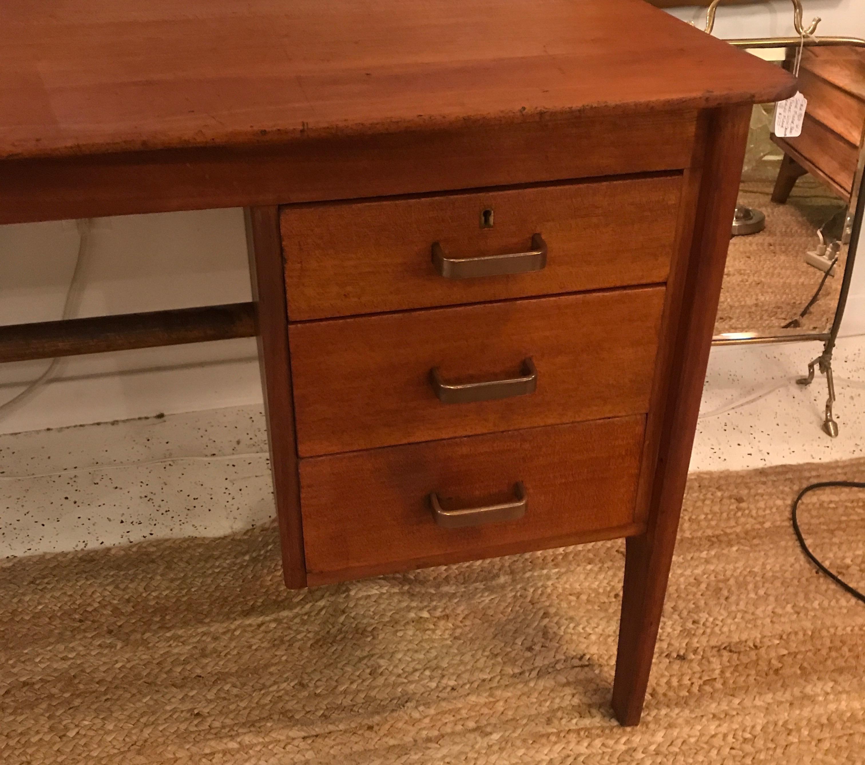 A craftsman made Mid-Century Modern desk by Gordon Russell, England 1950. The midcentury style desk with simple rectangular top with three side drawers with brass handles. Rare English midcentury piece.