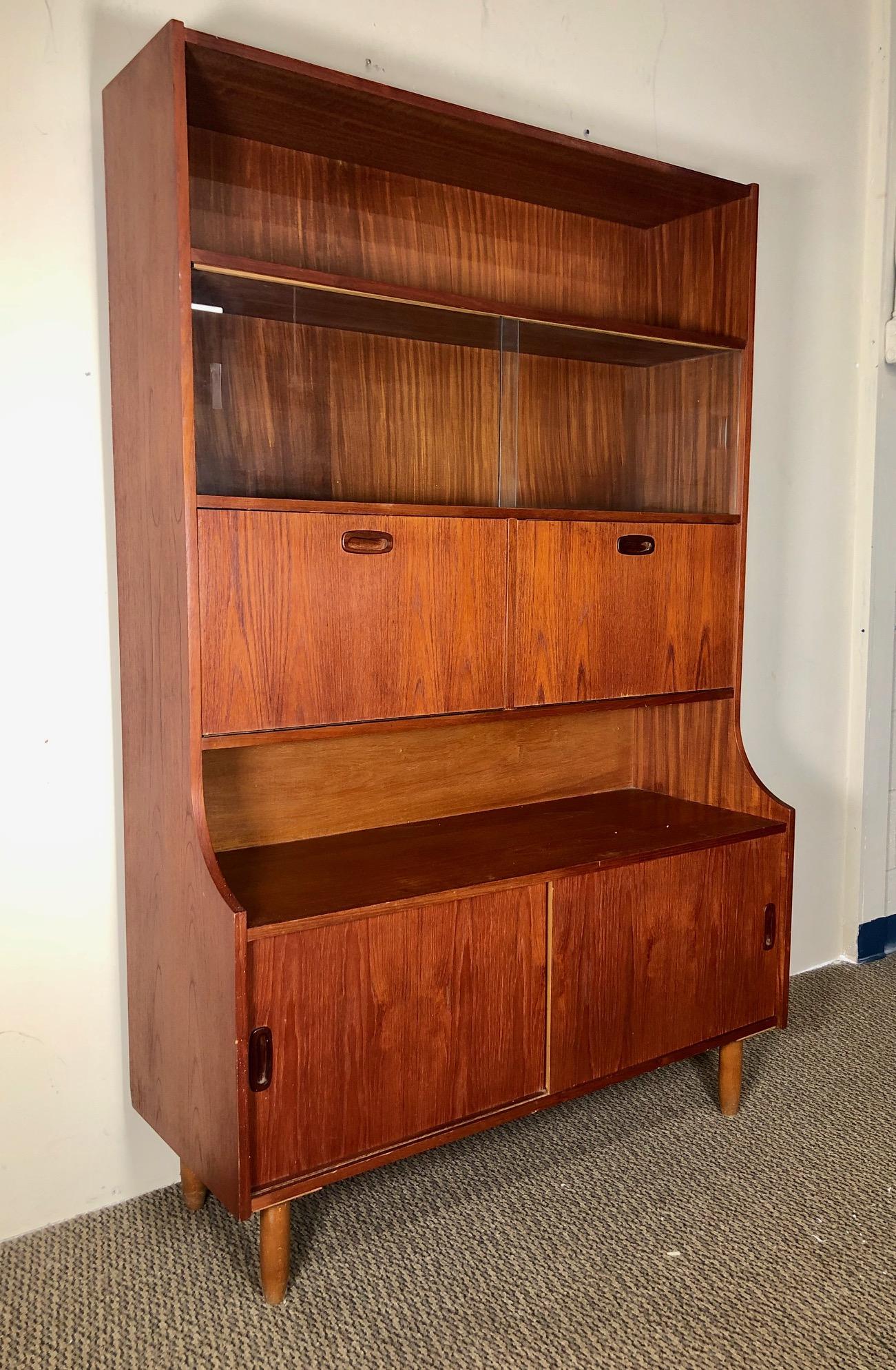 This is a beautiful teak cabinet, secretary and bar. 
Made by Ellman Furniture. Original label at the back. Featuring glass sliding doors at the top. A small drop down desk and a small drop down bar with light. The light needs to be rewired and