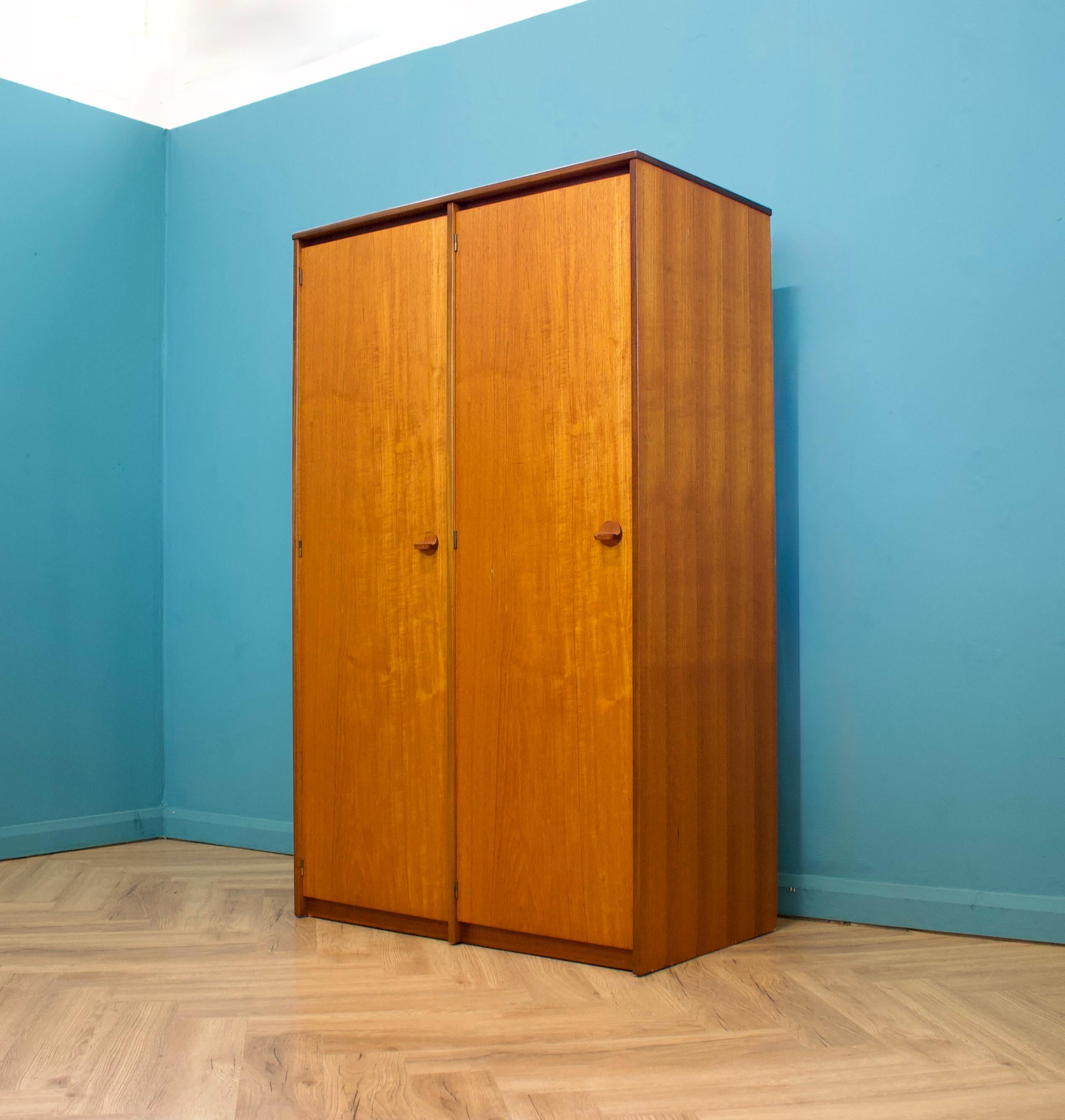 Armoire autoportante à deux portes en teck de Stag pour la gamme Cantata - conçue par John et Sylvia Reid.
Fabriqué dans les années 1960

Elle est équipée d'une tringle à linge d'un côté et d'étagères et de tiroirs de l'autre.
Le style de cette