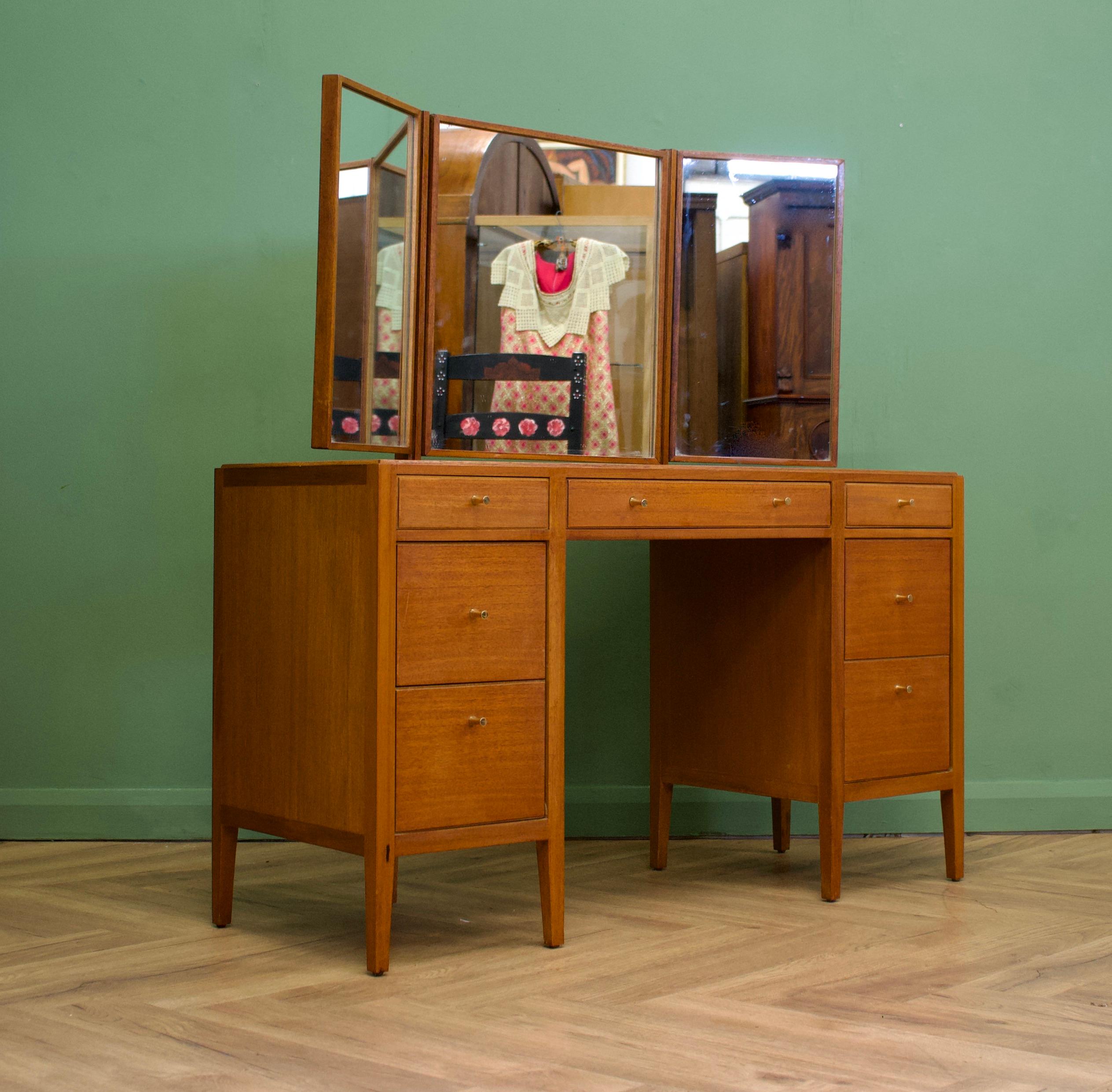 - Midcentury dressing table.
- Manufactured in the UK by Loughborough
- Retailed through the department store Heals, during the 1960s
- Made from Teak & Teak Veneer.

- Featuring 7 drawers and a triptych mirror.