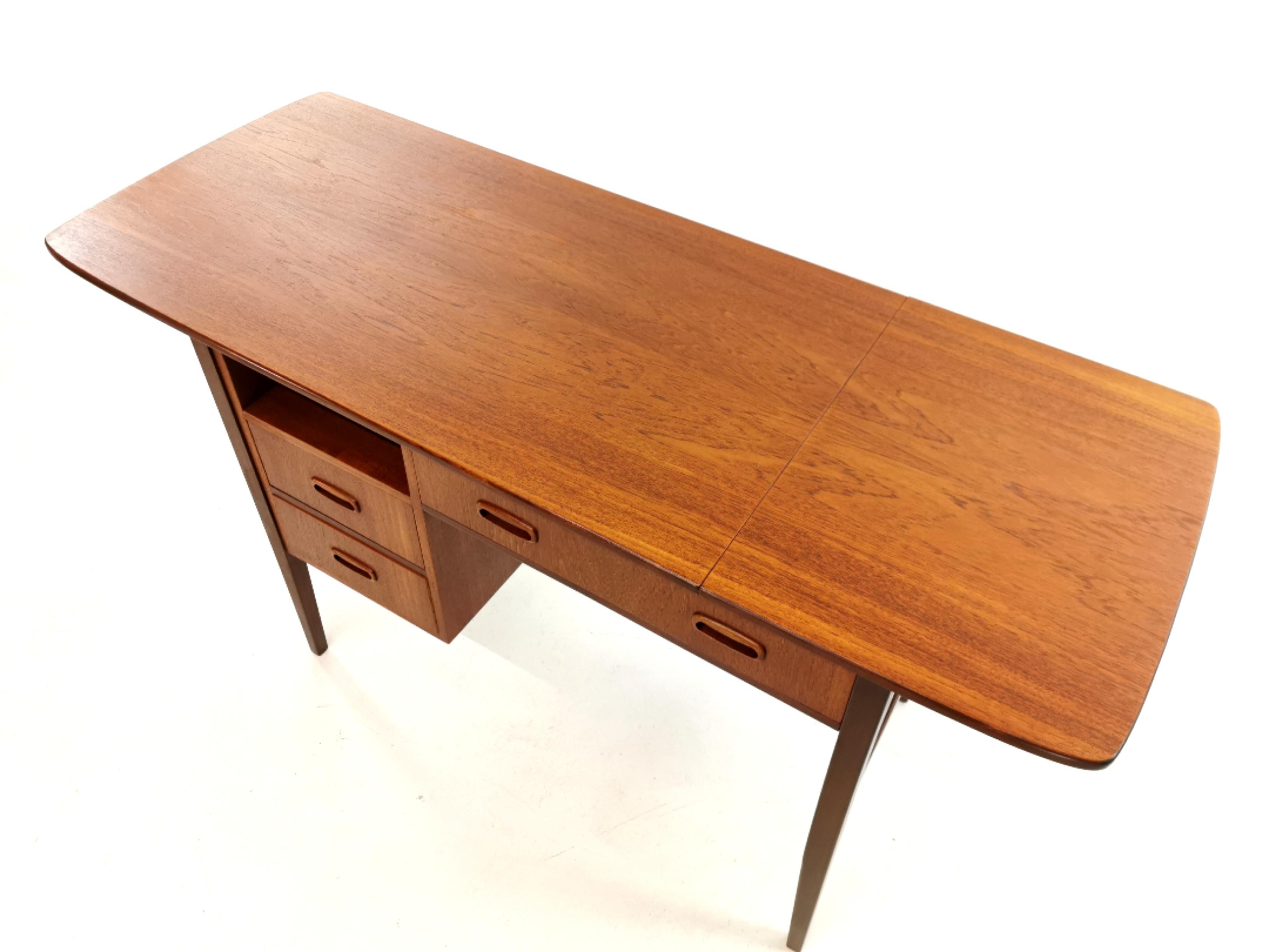 Danish style teak writing desk from the 1960s.
By London firm Grange. Made in the UK.
Compact with plenty of storage space. Features a desktop which slides left and right to raise or
lower the drop leaf.
