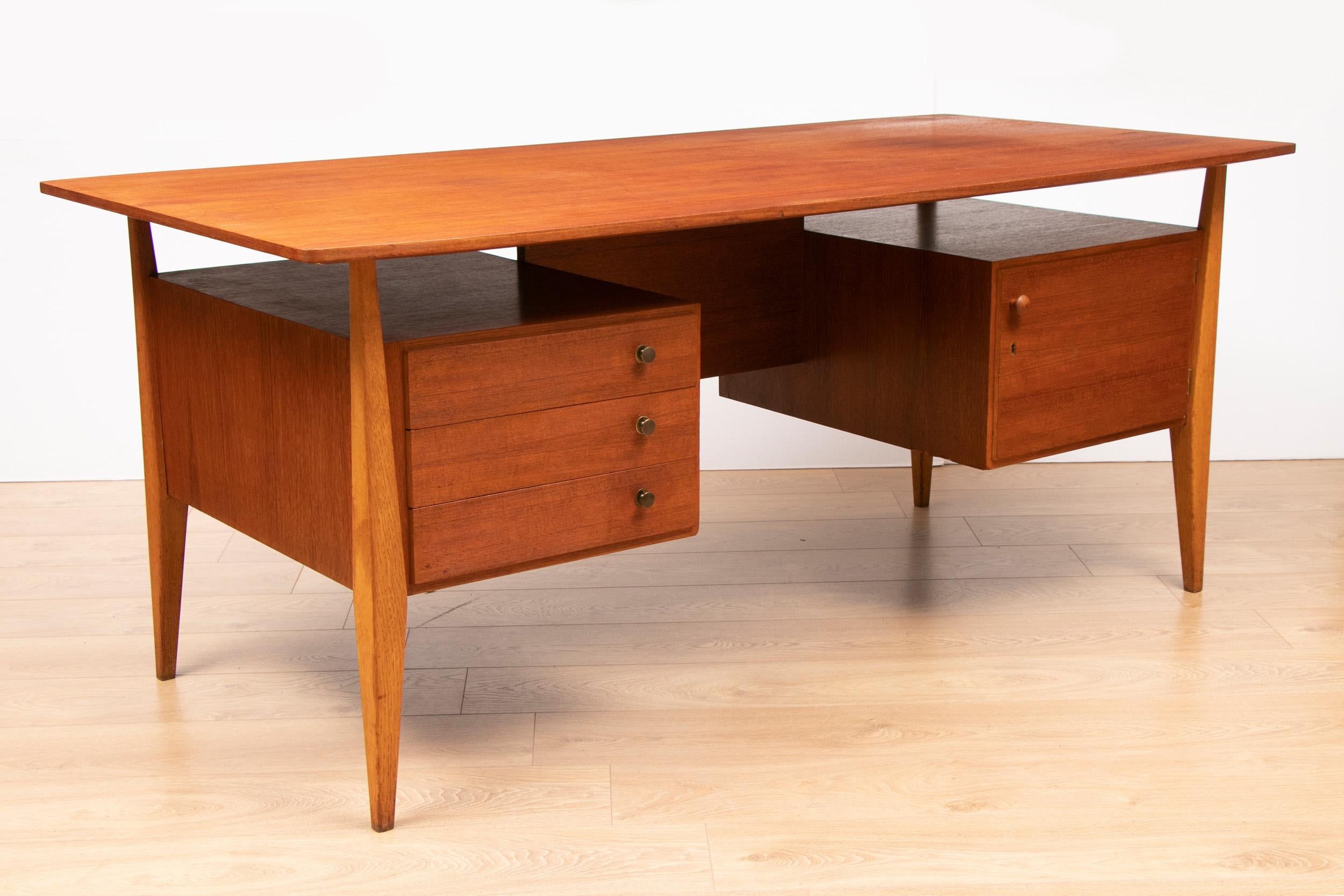 A gorgeous substantial midcentury teak executive floating desk with bookshelf. Stunning grain on worktop that floats on sculptured legs. 3 drawers and a cabinet with lock and key. Bookshelf on the back. Manufacturer unknown but there appears to be