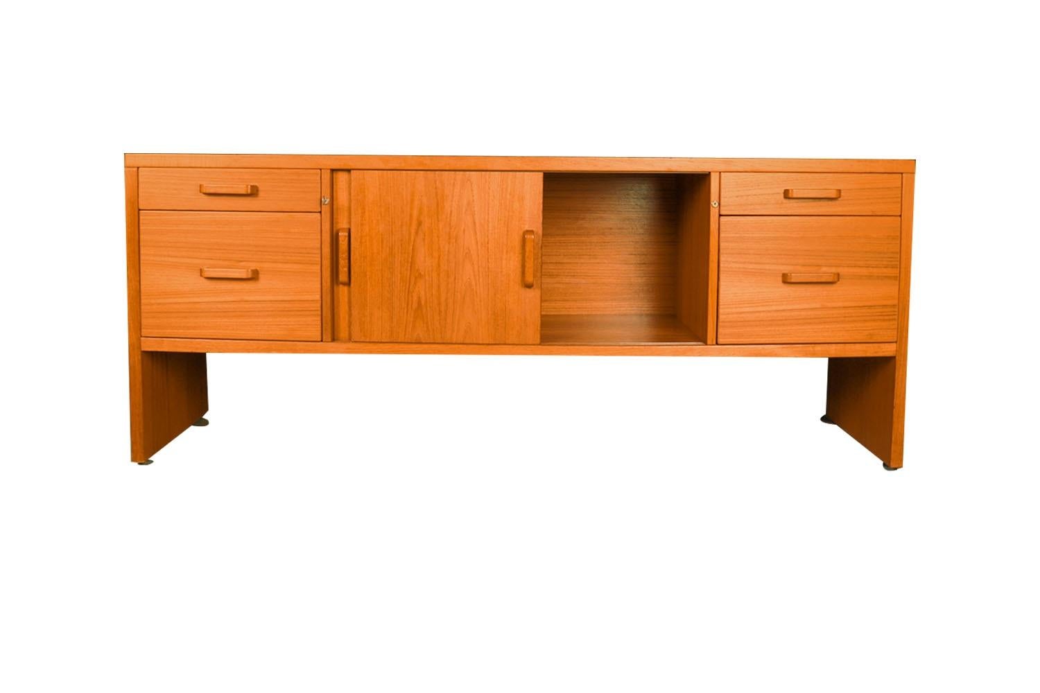 An exceptional teak file cabinet/credenza circa 1970's, made in Denmark. This absolutely stunning piece features a sliding double door cabinet with finished teak interior and spacious storage in the center flanked by two deep spacious file drawers