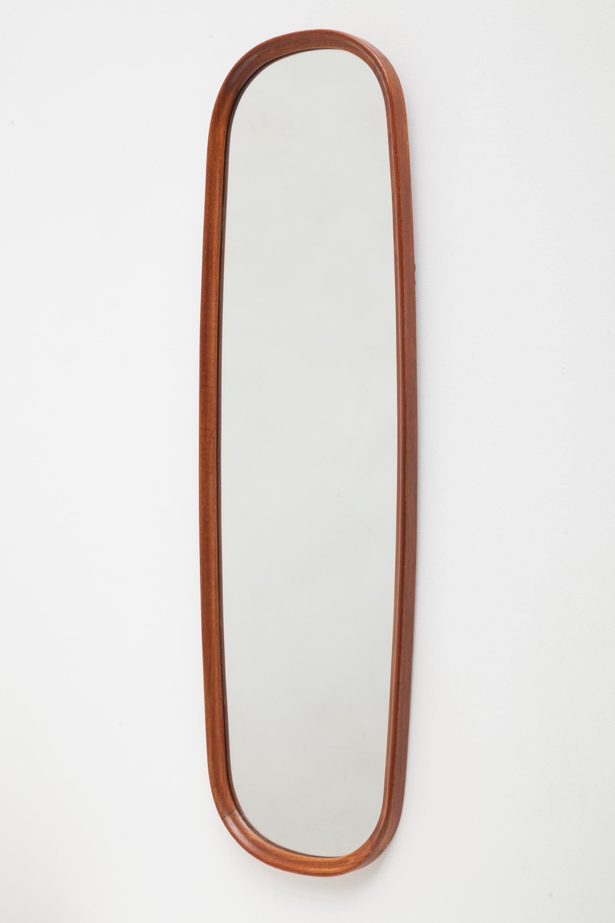 Vintage mid century teak wall mirror in an oval ellipse shape features brass hanging hardware. Real crystal glass.