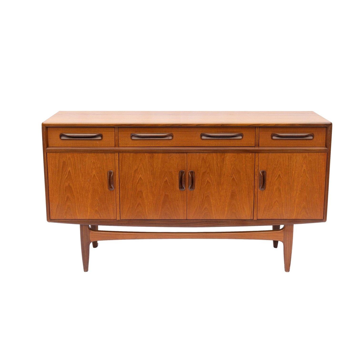 Mid-Century Modern teak Fresco sideboard designed by Victor Wilkins for G Plan, English, ca. 1960, with three frieze drawers, one long with fitted interior and two short, above four open cabinet doors; all with molded sculptural handles, on a Danish