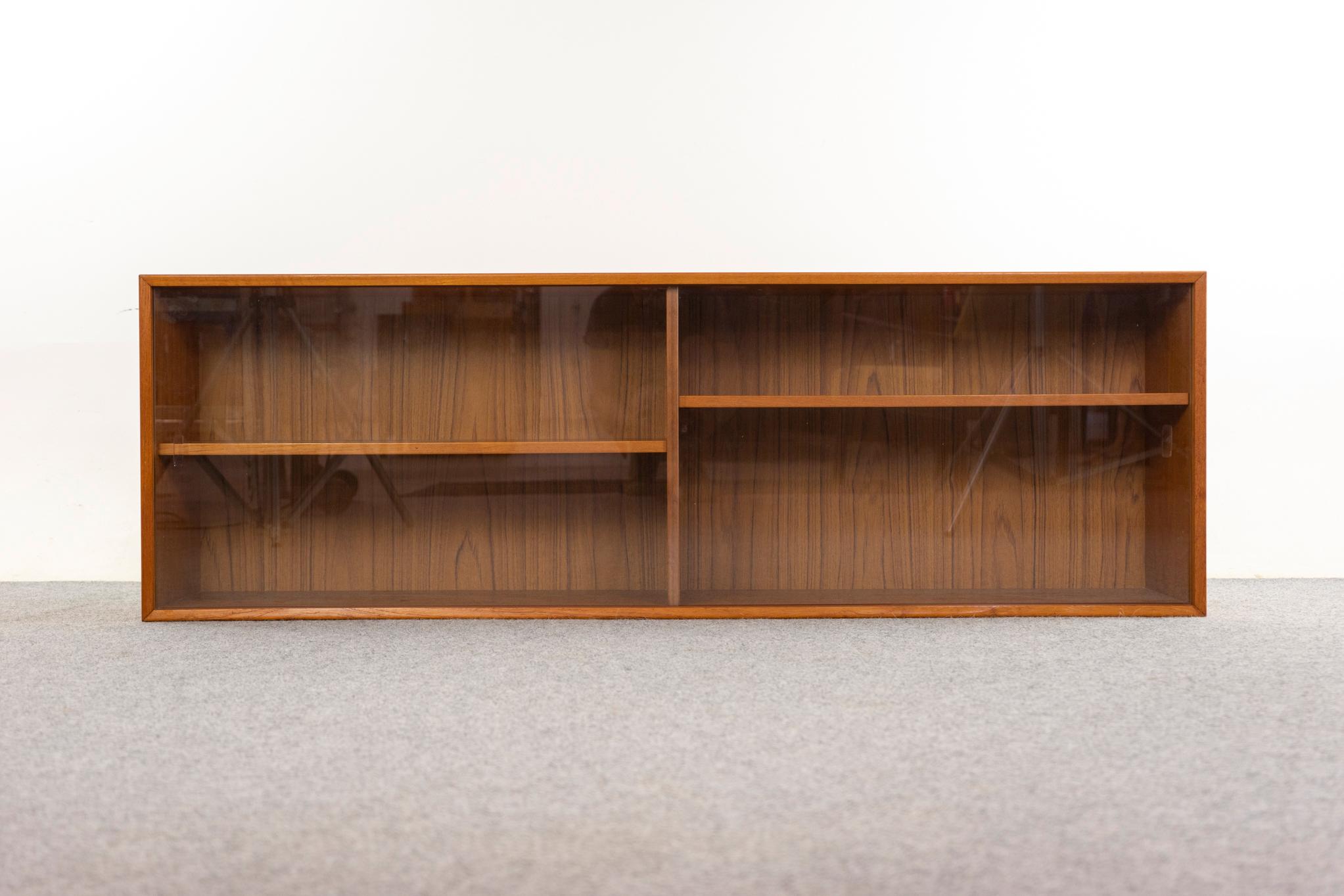 Cabinet de curiosité danois en teck et verre, vers les années 1960. Design/One simple et épuré avec placage assorti au livre sur l'ensemble du meuble. Portes coulissantes en verre à fonctionnement doux avec poignées encastrées. Étagères réglables.