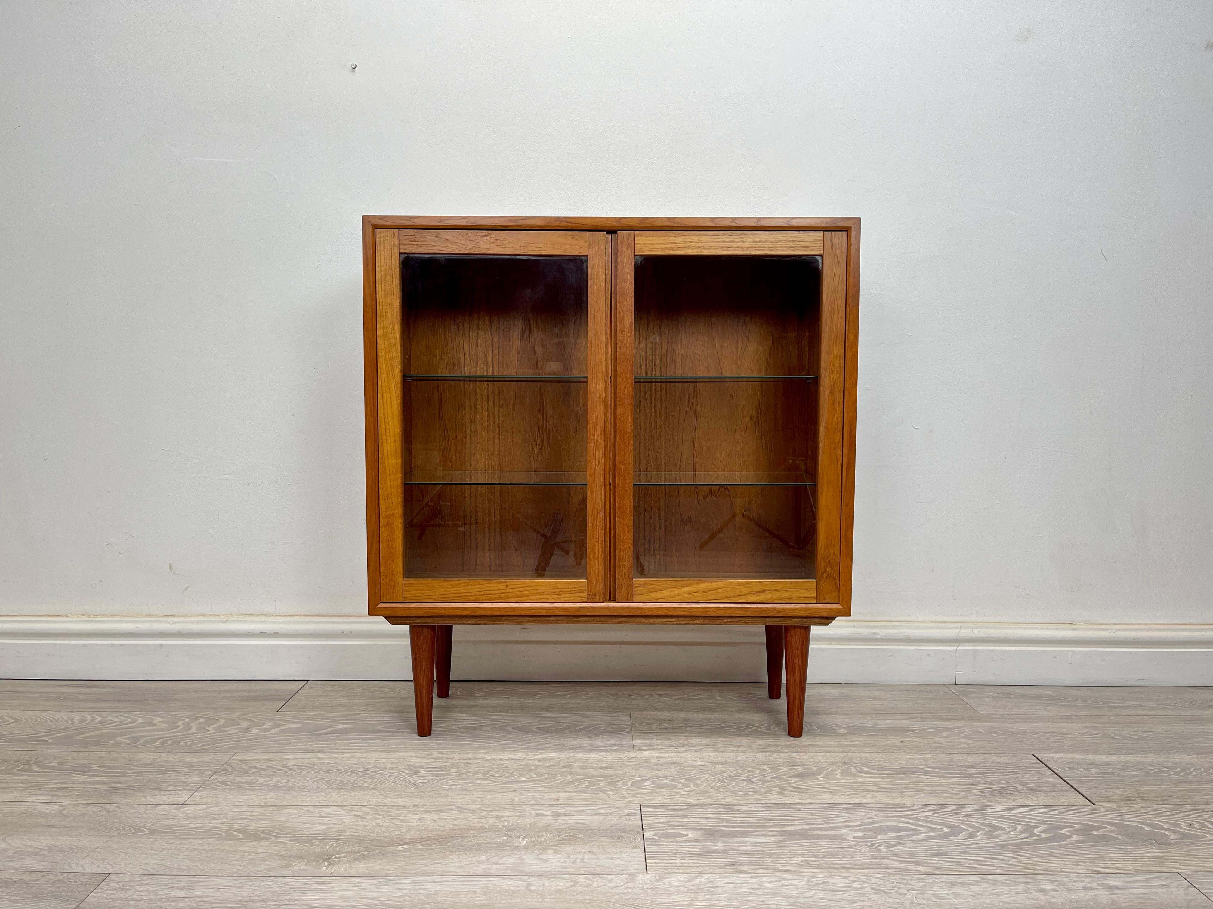 BOOKCASE
Midcentury Danish Teak Bookcase/ display cabinet by Poul Cadovius cir 1970 . The cabinet stands on round tapered legs has stunning grain and patin through , there two glazed doors with two adjustable glass shelves . 

Dimension 
Height-