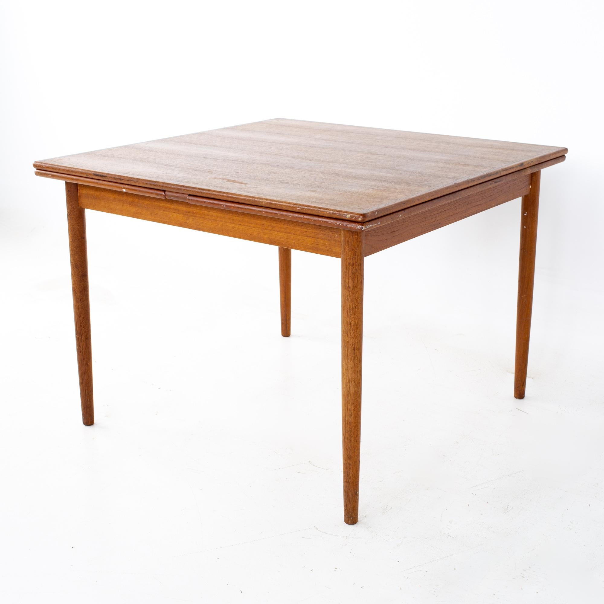 Mid century teak hidden leaf expanding dining table
Table measures: 39.5 wide x 39.5 deep x 28.5 inches high; each leaf 18 inches wide, making a maximum table width of 75.5 inches when both leaves are used, and has a chair clearance of 24.25 inches