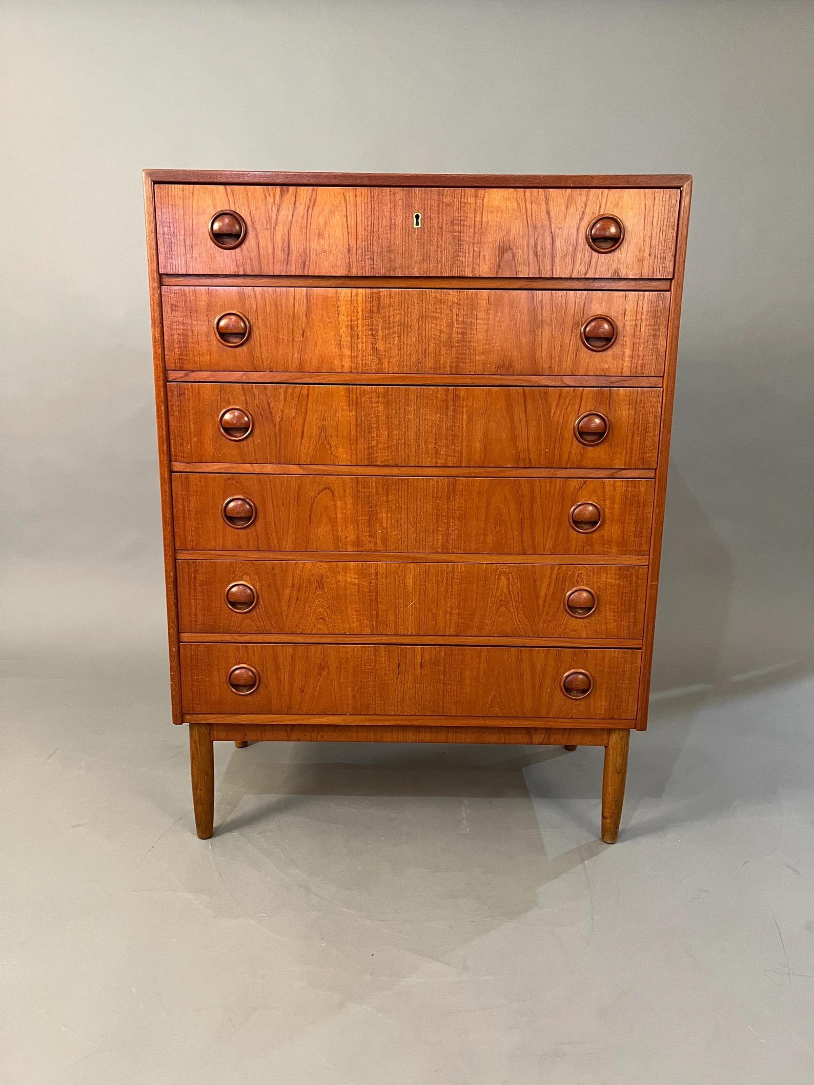 Enhance your living space with this stunning mid-century highboy teak dresser from Denmark. Crafted in the 1960s, this dresser features six spacious drawers, providing ample storage for your belongings. The teak wood exudes a warm and timeless