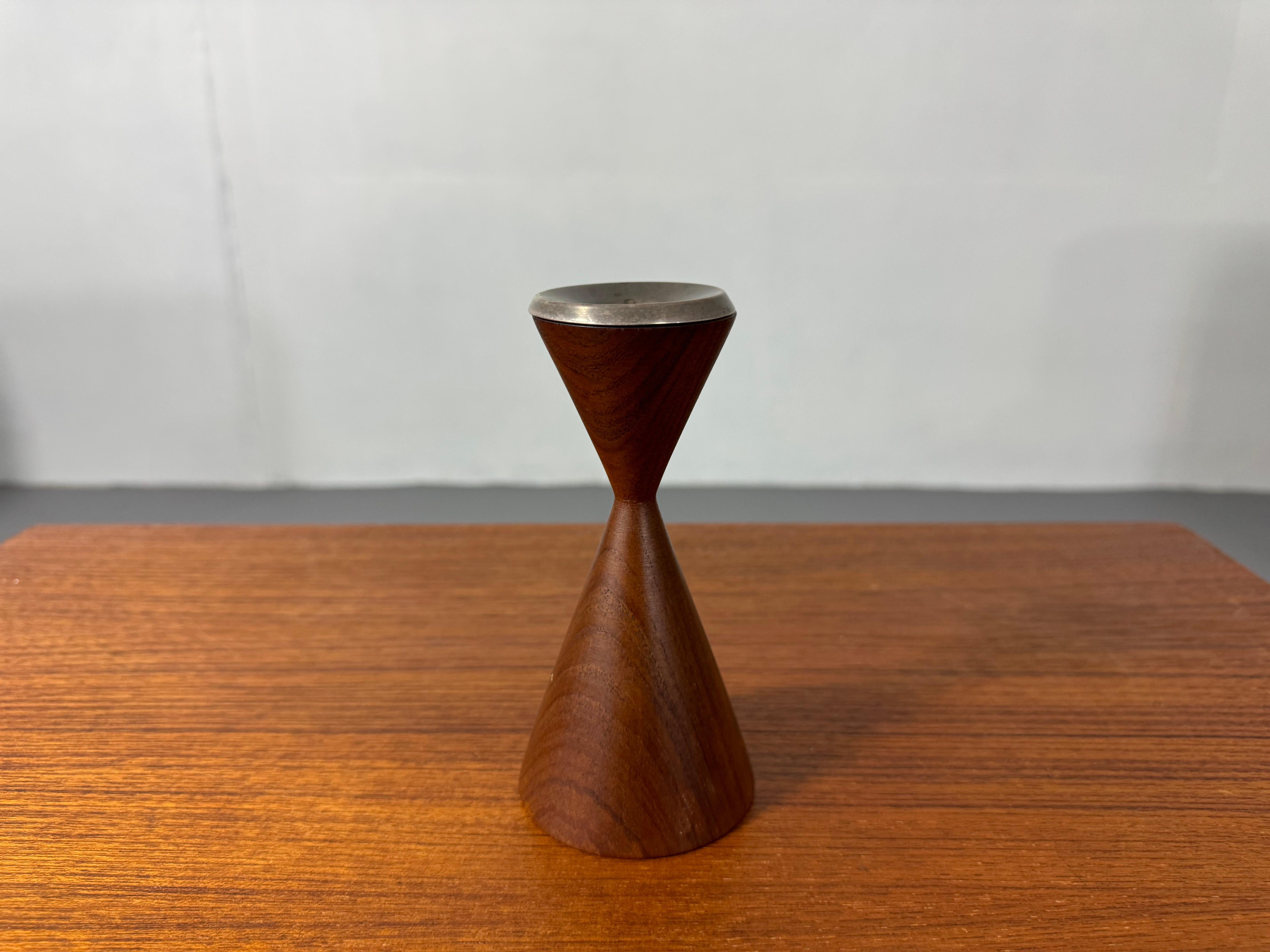 Mid-Century Teak Hourglass Candle Holder with Patinated Metal Top

This elegant teak candle holder features a distinctive hourglass shape, showcasing the rich, warm hues and natural grain patterns typical of high-quality teak wood. The solid teak