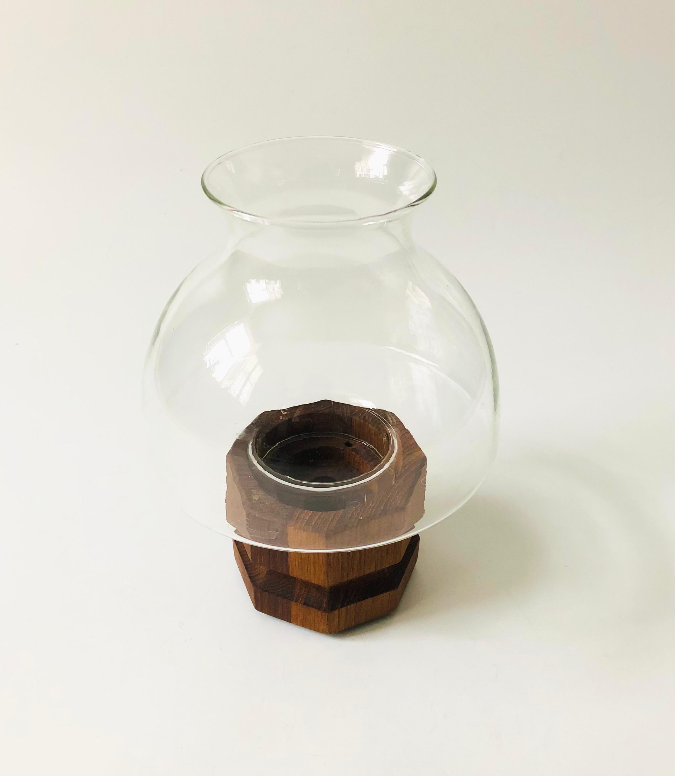 A mid century hurricane candle holder by Selandia Designs. Features a glass top that sits within a teak base. The base includes 3 sizes of recessed circles to hold different sizes of hurricane candles or a standard taper candle.

  