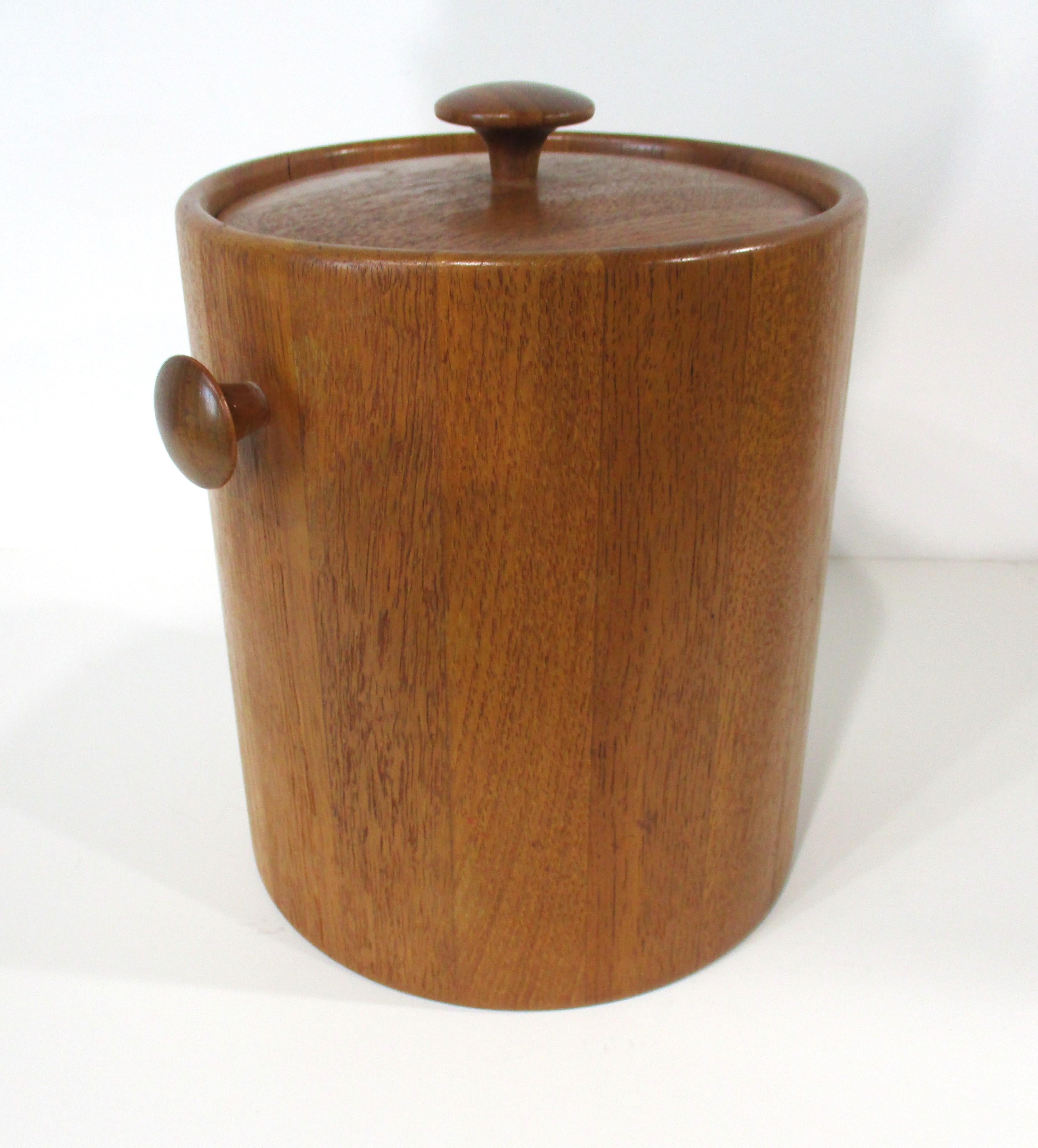 A teak wood ice bucket with matching knob on the lid and sides for easy use having a foam insert to keep things cool . Also inside is a removeable for cleaning plastic bucket which slips in and out . Designed in the manner of the Dansk company made