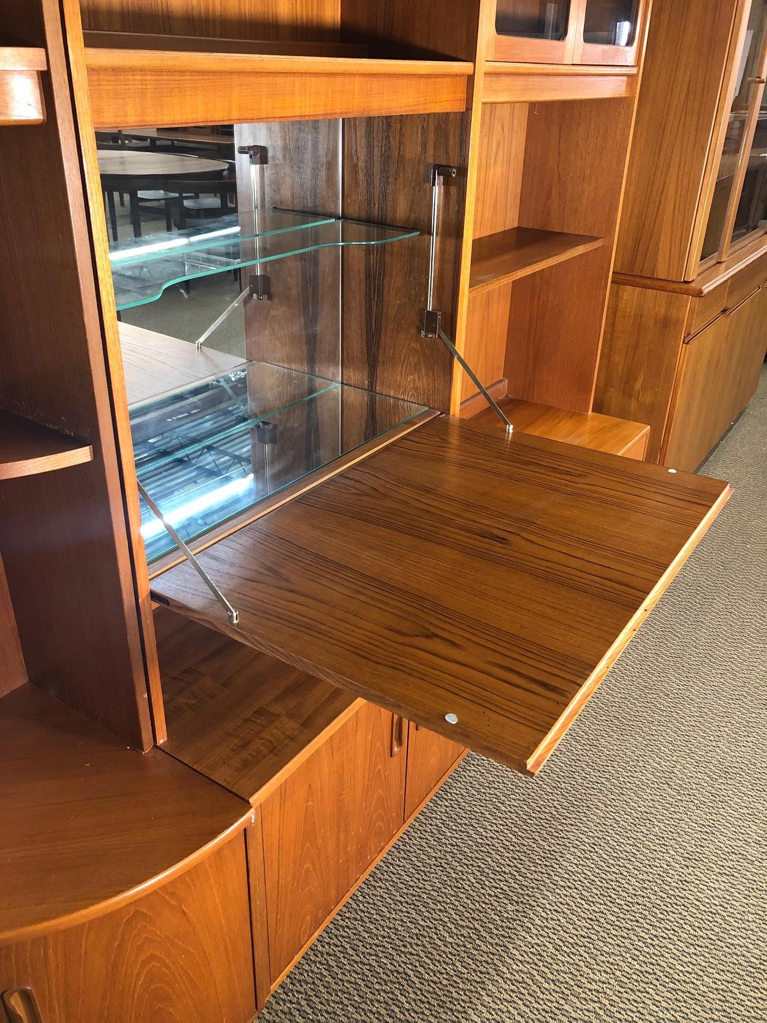 Fantastic teak wall unit made by G Plan. Made in England. It includes 2 base unit, 2 top units, 1 corner piece with top and bottom. Features 1 drop down unit that can be used as a bar. The base has 2 two-door cabinets. The shelves are