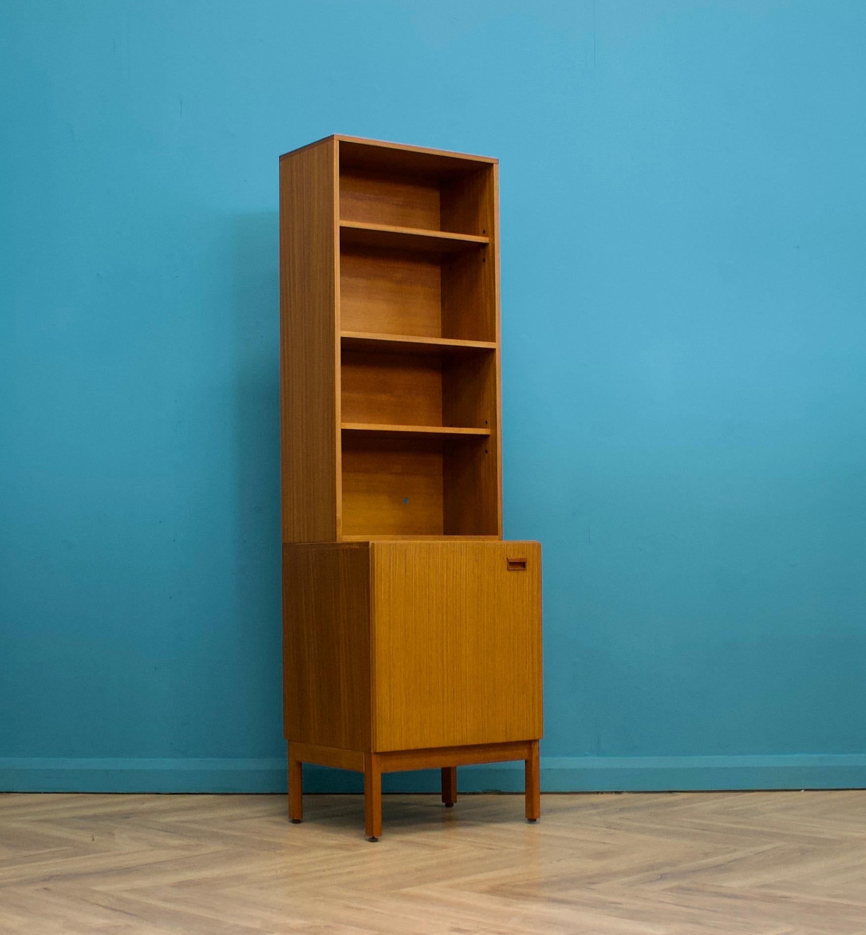 A mid century teak narrow bookcase from Austinsuite, circa 1960s



The low profile cupboard door handles are made from sold wood

Featuring three shelves and additional storage in the bottom cupboard



There is a matching drinks cabinet which is