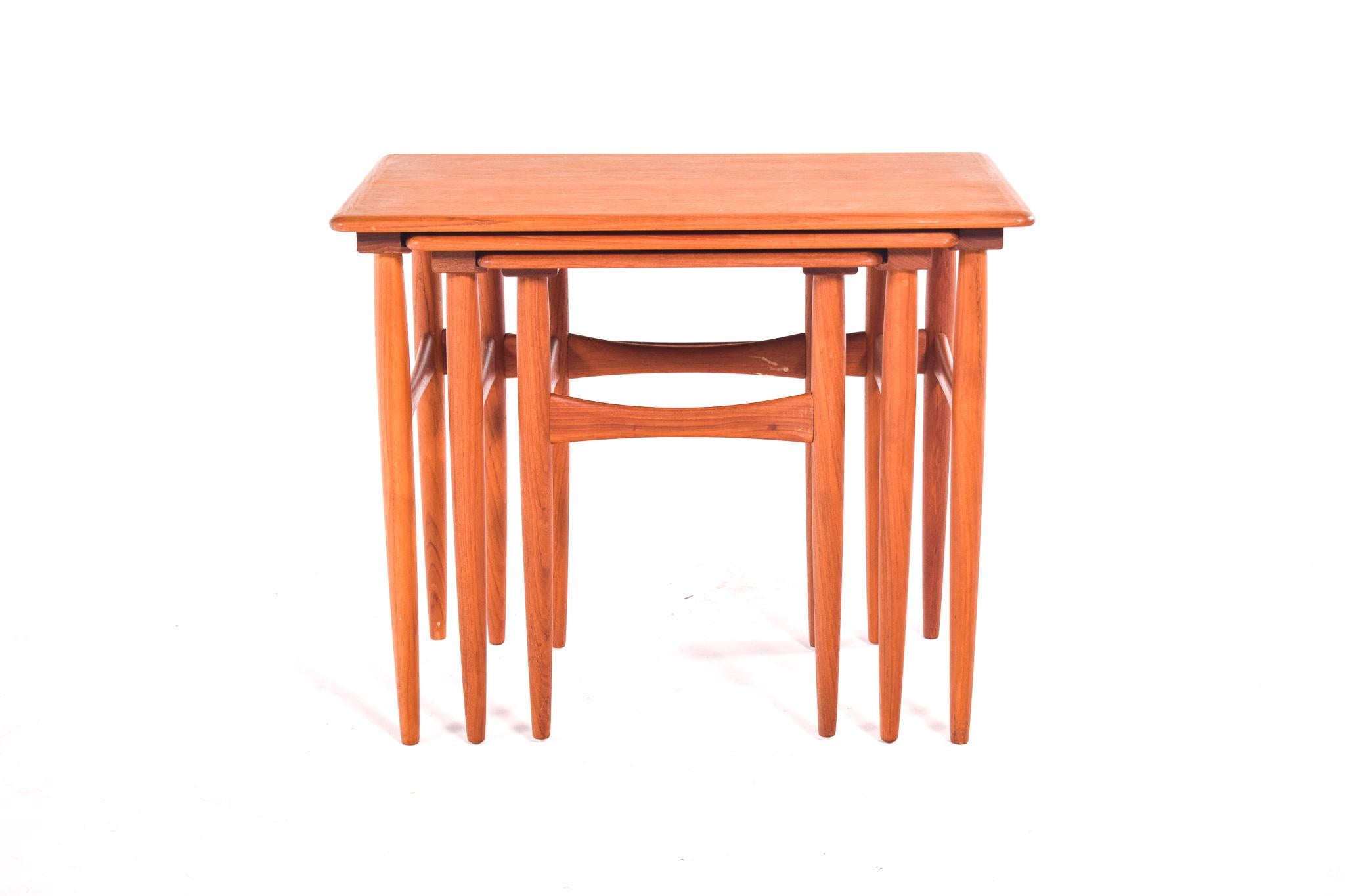 A set of three Danish modern teak nesting tables, 1960's. Beautiful tables, well designed by Kai Kristiansen. With tapered legs and bowtie stretchers. The tables slide easily into each other, so that they take up little space. Elegant piece to