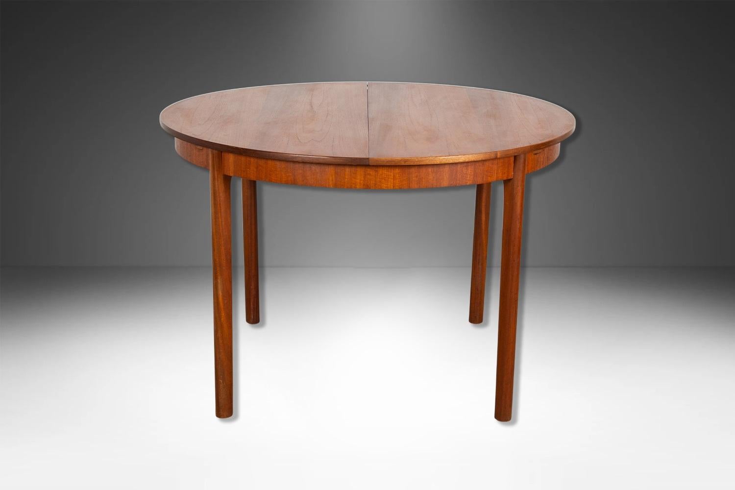 Beautiful Mid-Century Modern dining table by AH McIntosh of Kirkcaldy, circa 1960's. Amazing design and construction detail, with one built-in self-storing leaf. With modernist elegant lines, this round dining table measures 44 7/8