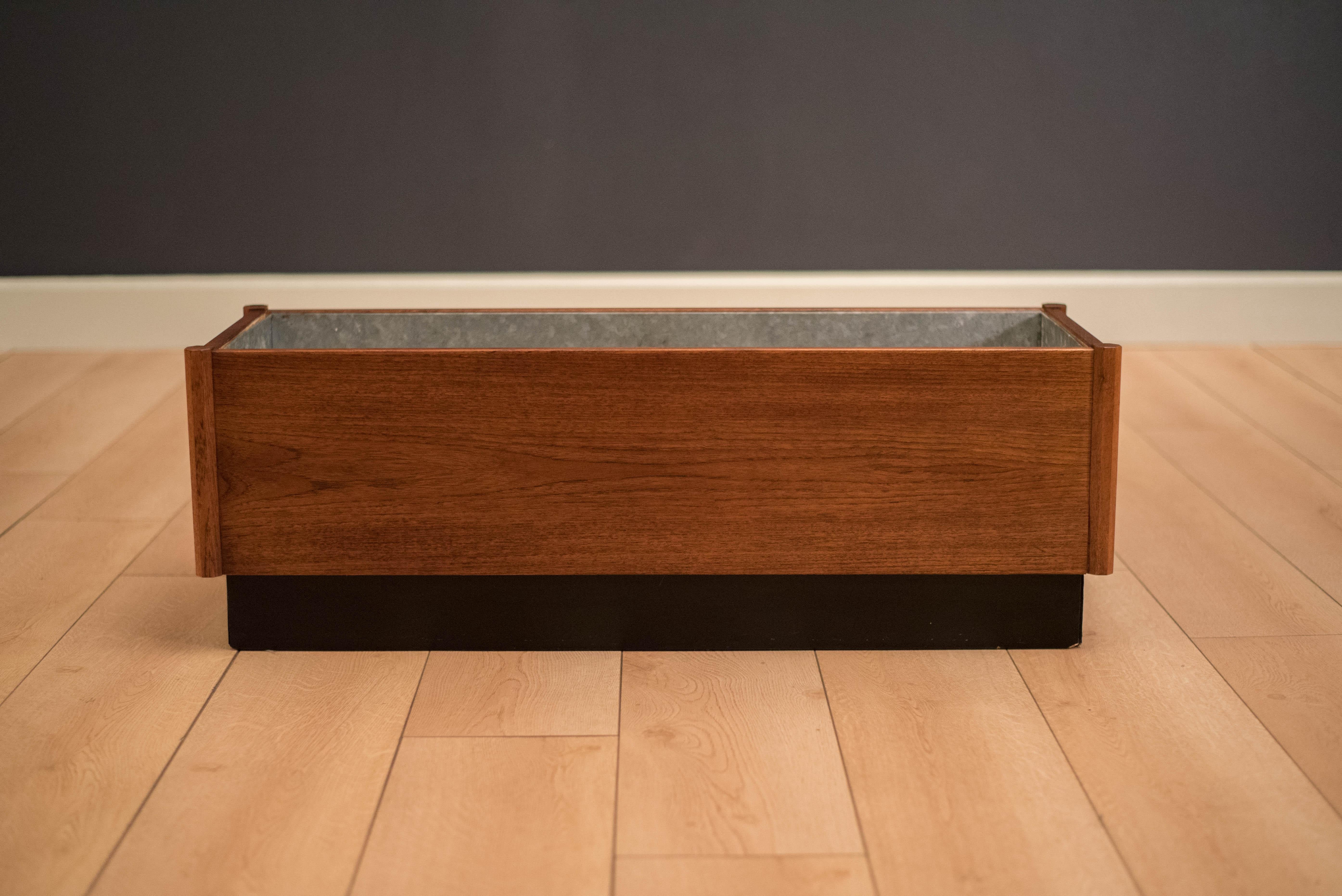 Vintage rectangular planter box in teak with black plinth base. This decorative piece includes a removable galvanized insert tray and is recommended for indoor use. 

Interior tray: 33.5