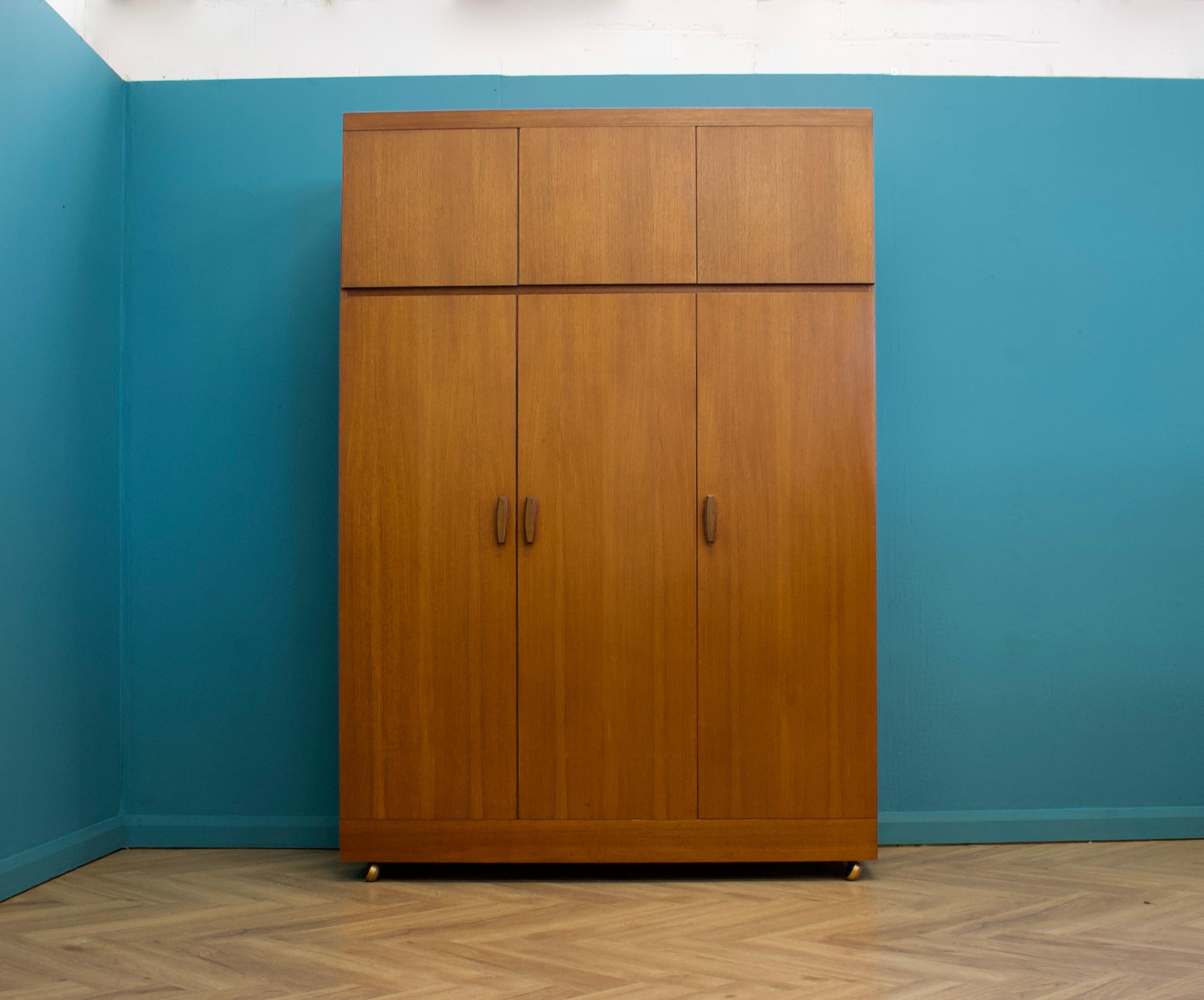 A freestanding triple door taller than usual teak wardrobe from G Plan from the Quadrille range - circa 1960s


Fitted out with a clothes rail to one side, shelves and drawers to the other 
A full length mirror is attached to one door 
There is also