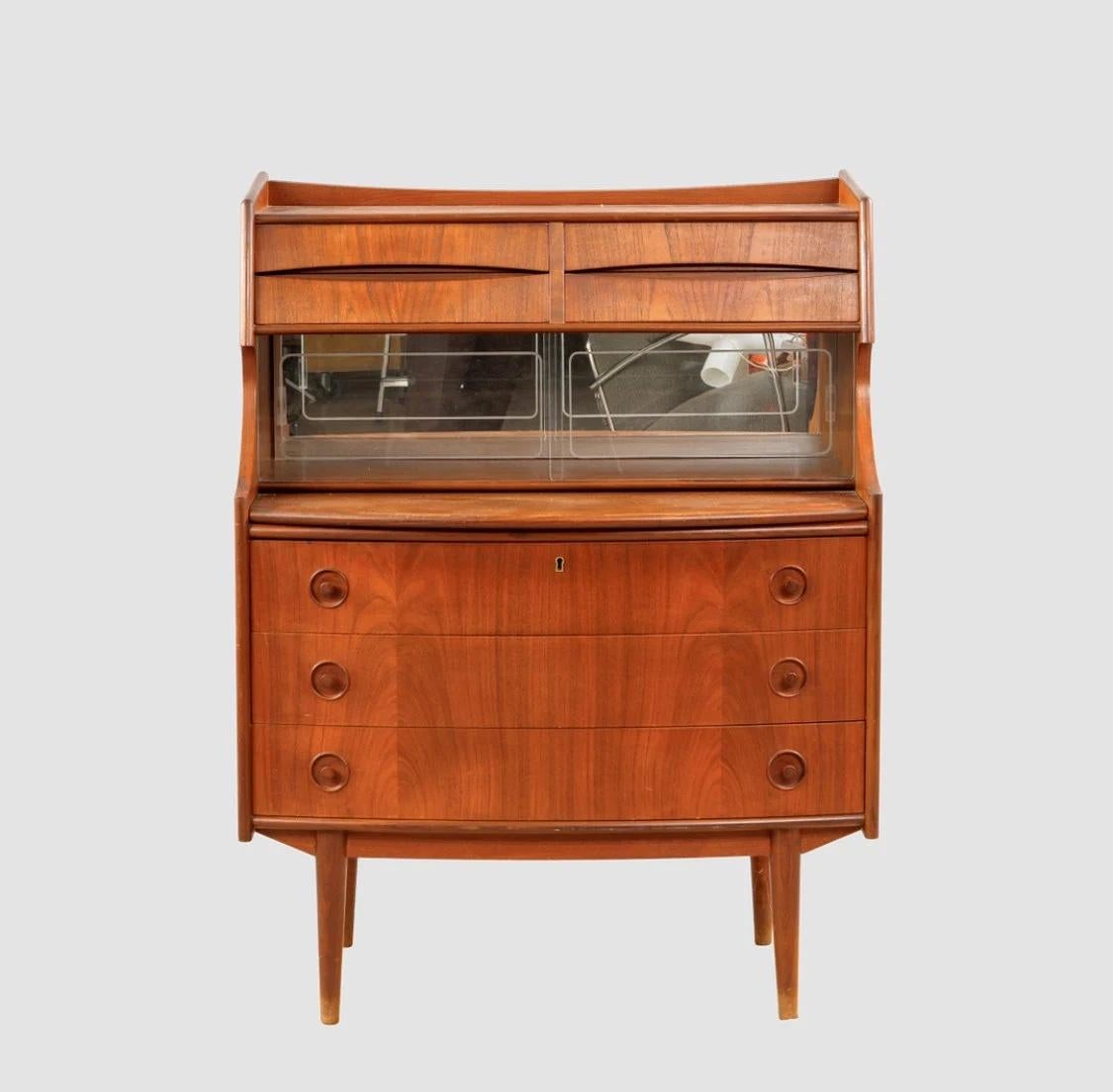 Esta secretaria de teca de mediados de siglo es un mueble bonito y funcional que combina estilo y funcionalidad. Fabricada en Dinamarca, esta original pieza tiene un diseño escandinavo único y está hecha de teca de alta calidad para mayor