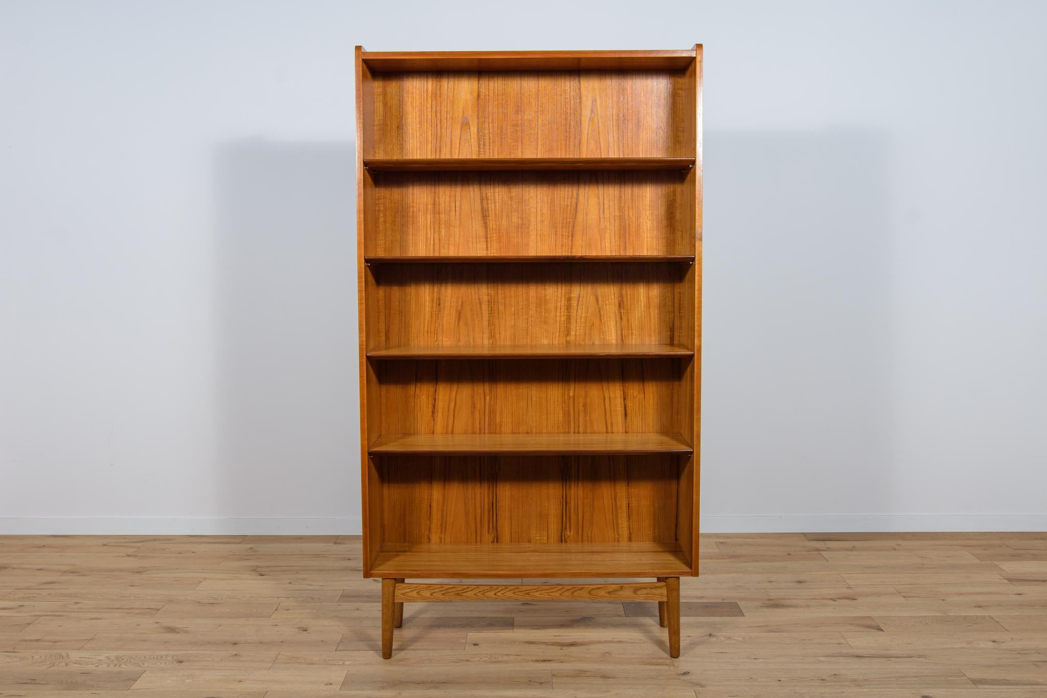 
Teak veneer bookcase designed by Johannes Sorth for Bornholm, Denmark in the 1960s. Bookcase with five shelves (adjustable height) tapering towards the top into a cone shape. The bookcase is mounted on legs, connected by a profiled strip. Furniture
