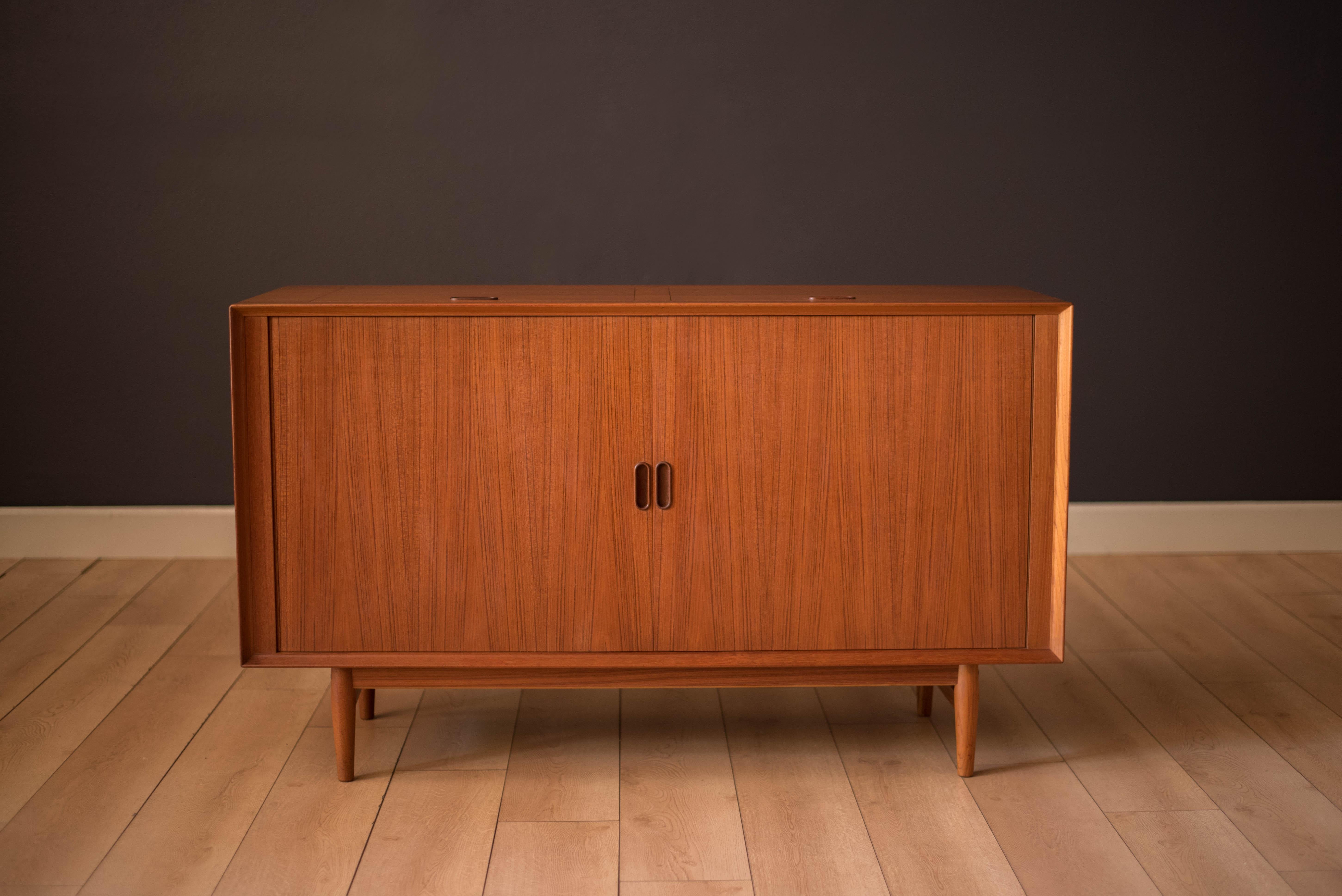 Mid-century record console cabinet in teak designed by Arne Vodder for Sibast, Denmark. This unique media cabinet features sliding tambour doors and two flip top compartments with signature sculpted handles. Includes a middle console shelf and LP