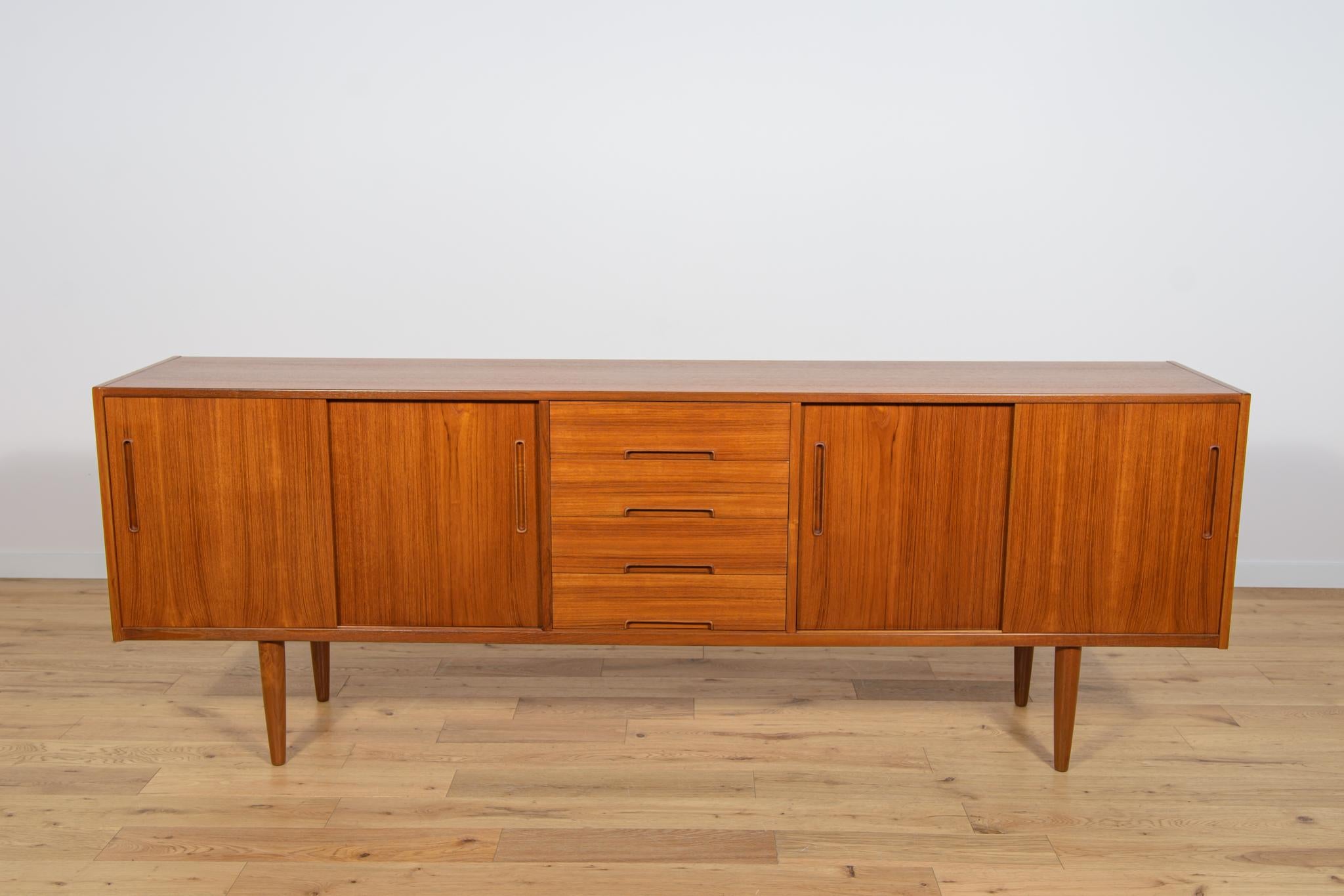 This mid-century Swedish designed sideboard was designed by Nils Jonsson and manufactured by Hugo Troeds. It is made of teak and features two cabinet with four sliding doors the middle in they find four drawers. Completely restored. Sideboard