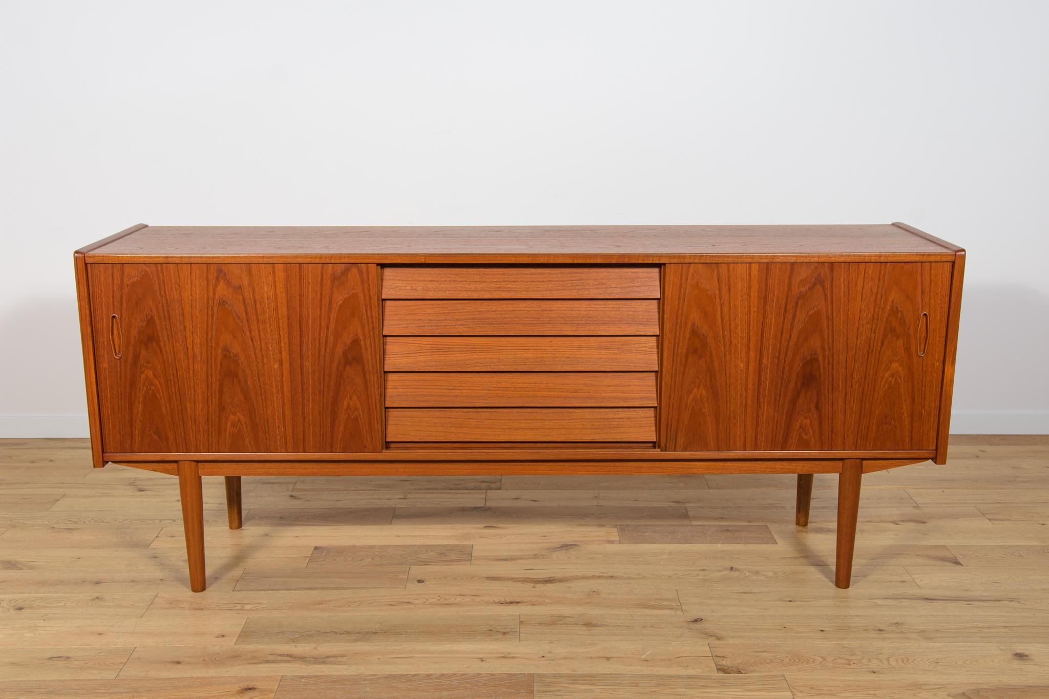 Questa credenza svedese di metà secolo è stata disegnata da Nils Jonsson e prodotta da Hugo Troeds, in Svezia. È realizzata in teak e presenta due ante scorrevoli e cinque cassetti. L'altezza dei ripiani è regolabile. La credenza è stata sottoposta