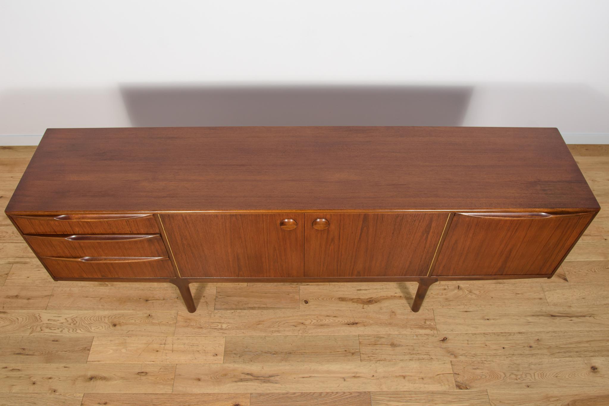 Ce buffet en teck du milieu du siècle, conçu par Tom Robertson, a été produit en Grande-Bretagne par Mcintosh dans les années 1960. Le buffet comporte trois tiroirs sur le côté gauche, une armoire au milieu, un bar et un plan de travail coulissant