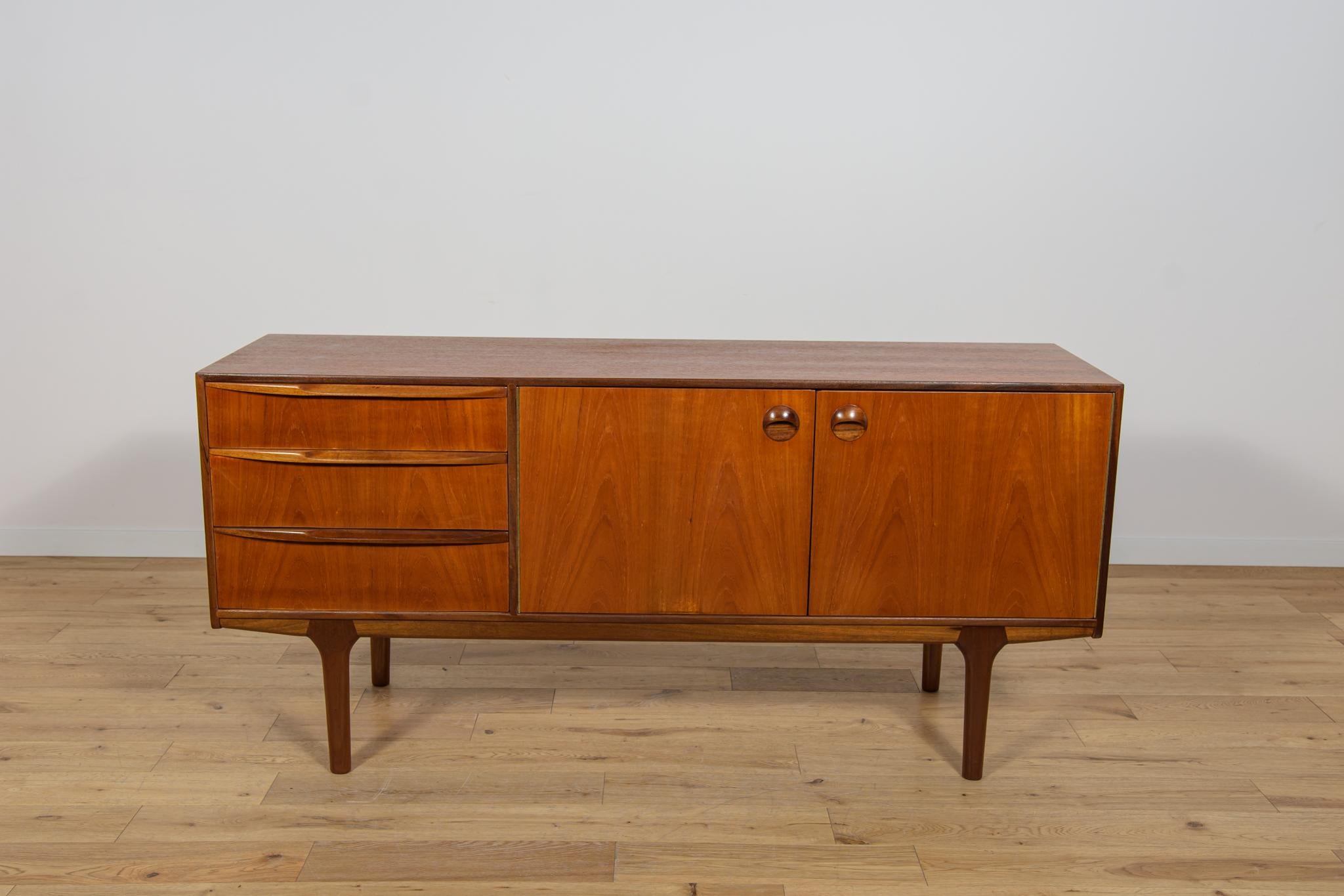 Questa credenza di metà secolo in teak è stata prodotta in Gran Bretagna, su disegno di Tom Robertson.   Mcintosh negli anni '60. La credenza ha tre cassetti e un armadietto. Credenza in legno di teak con maniglie profilate. Gli elementi in teak