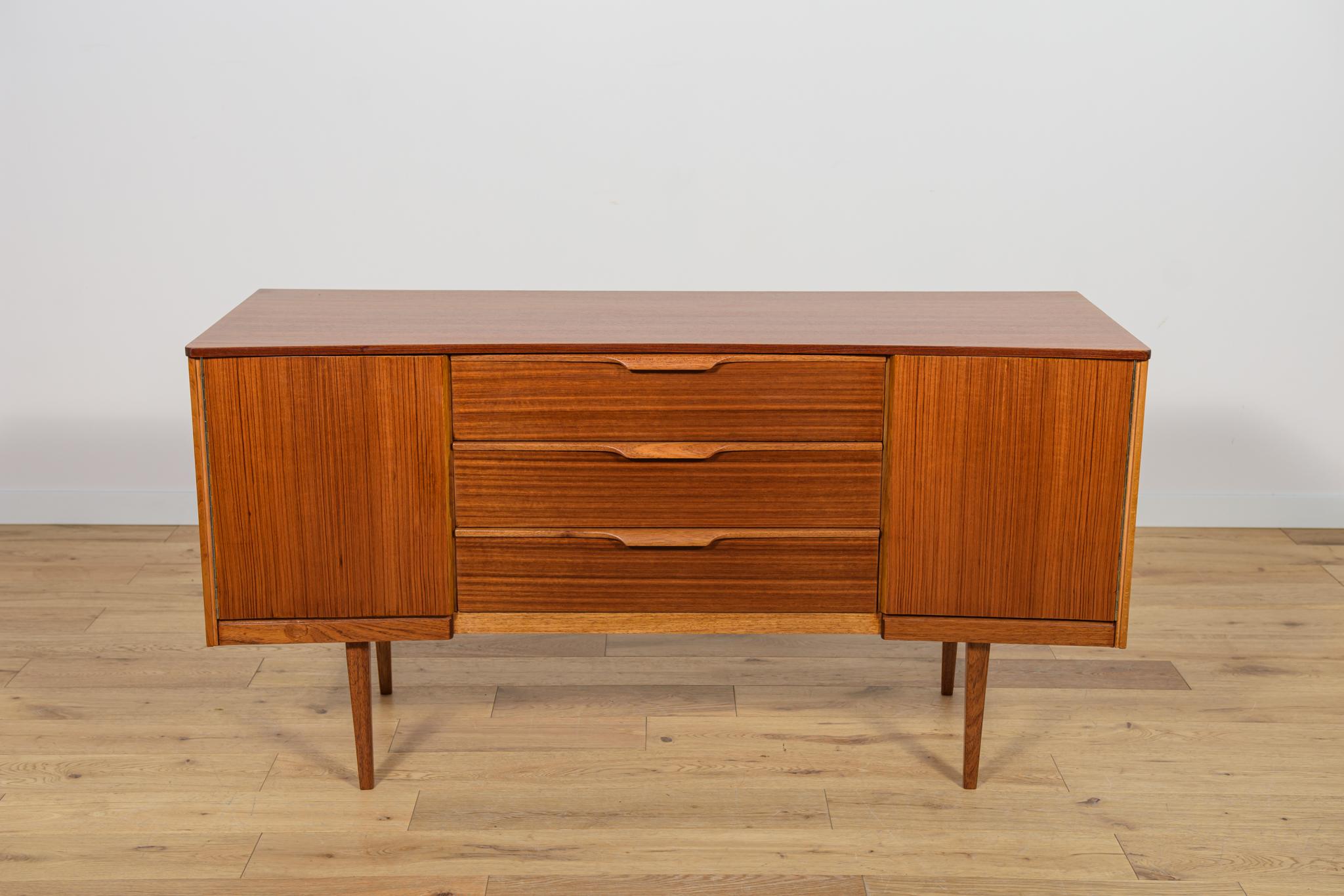 Petit buffet fabriqué dans l'usine britannique Austinsuite dans les années 1960. La commode se compose de deux meubles avec des étagères sur les côtés et de trois tiroirs au milieu. Les meubles ont fait l'objet d'une rénovation complète de la