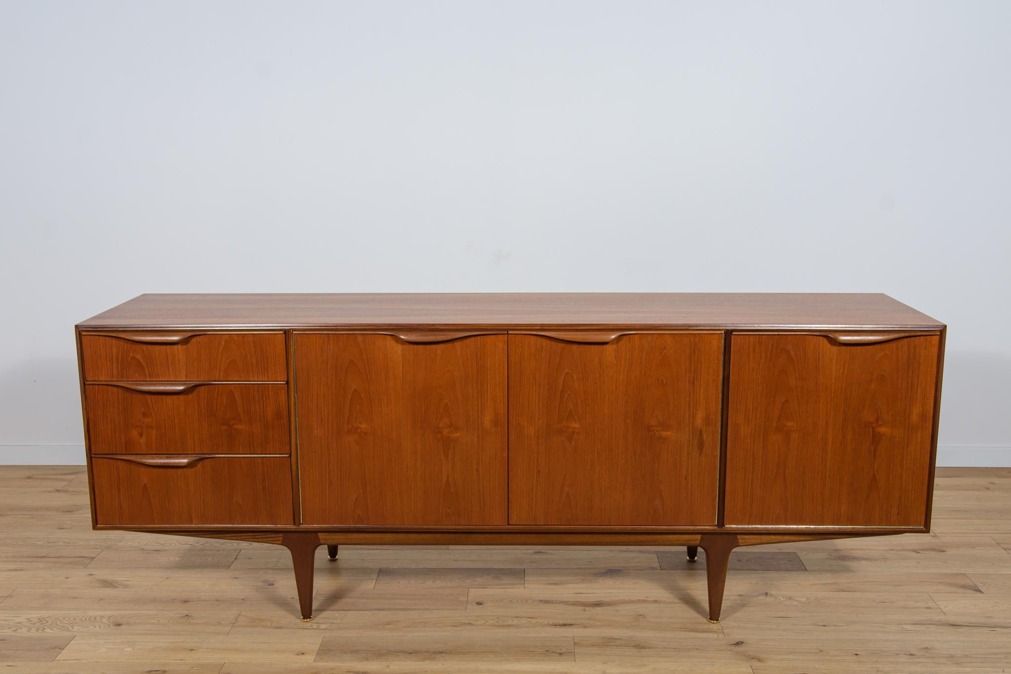 
This mid-century sideboard in teak was produced in Great Britain by Mcintosh in the 1960s. The sideboard has three drawers and a cabinet, on the right side there is a bar and a pull-out top. Sideboard made of teak wood with profiled handles. The