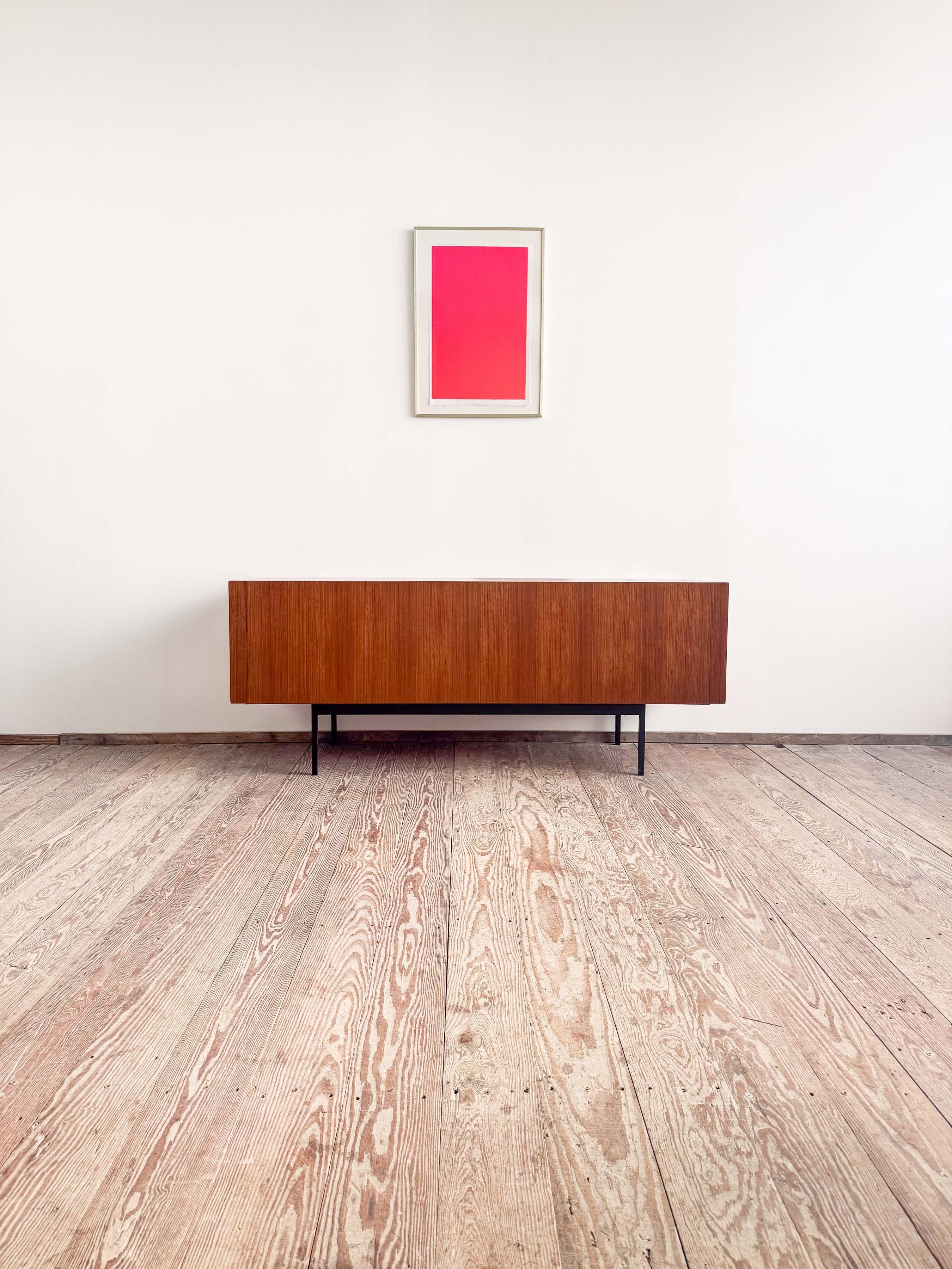 Dimensioni 174x56x70 cm (LxPxH)
Dimensioni: circa 68,5 x 22 x 27,6 pollici

Elegante credenza Dieter Wäckerlin in teak con base in metallo verniciato nero. Intarsio realizzato in acero. Si tratta di una rara versione più piccola della grande