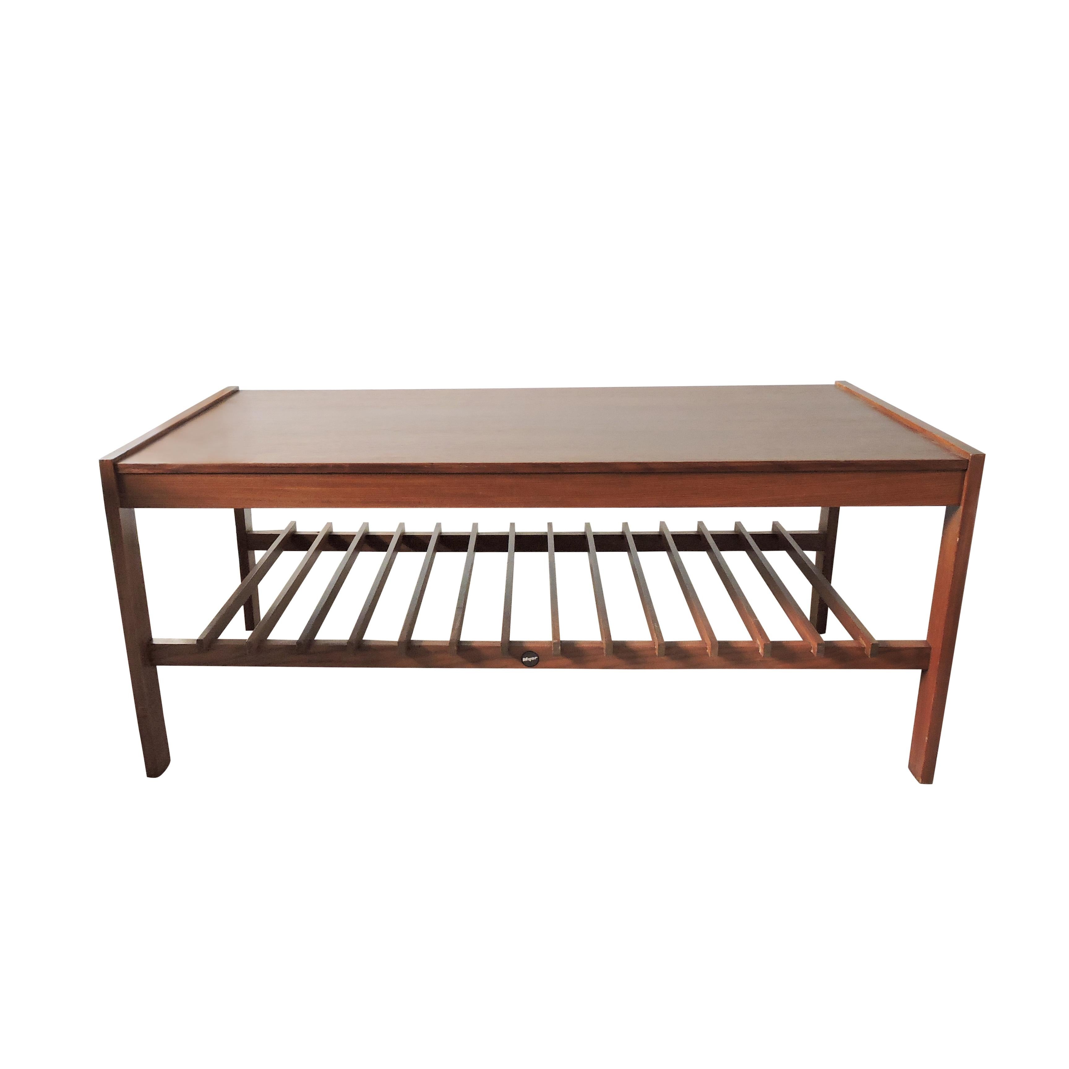 This vintage Danish style slatted coffee table was designed and manufactured by Myer in the UK. The table features a top board with a teak finish and a slatted magazine rack.
