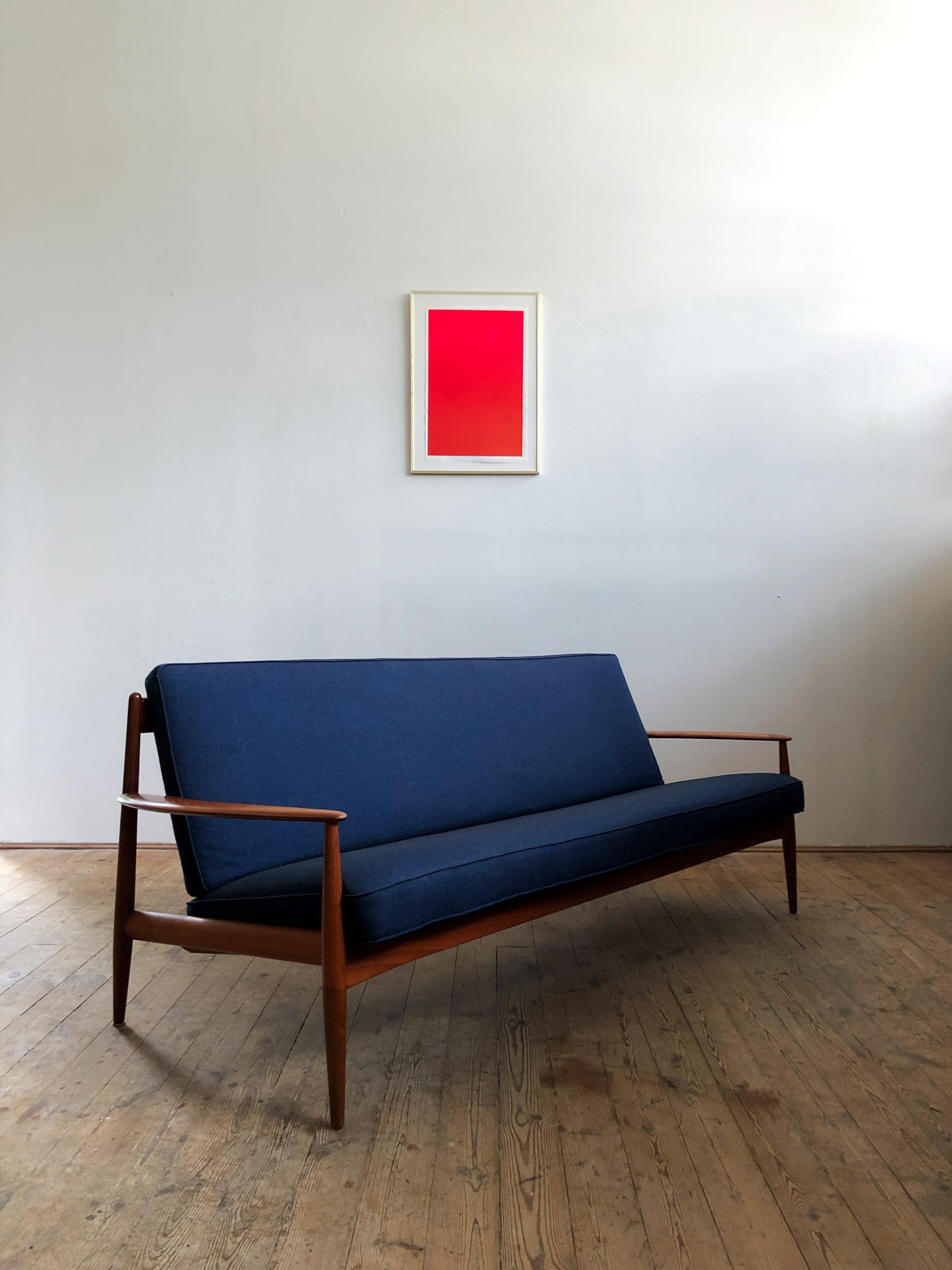 Early vintage version of Grete Jalk's teak sofa produced by France & Daverkosen that shows high quality Danish craftsmanship. The sofa comes in its original state with original -rather soft- spring-loaded padding and original dark blue upholstery.
