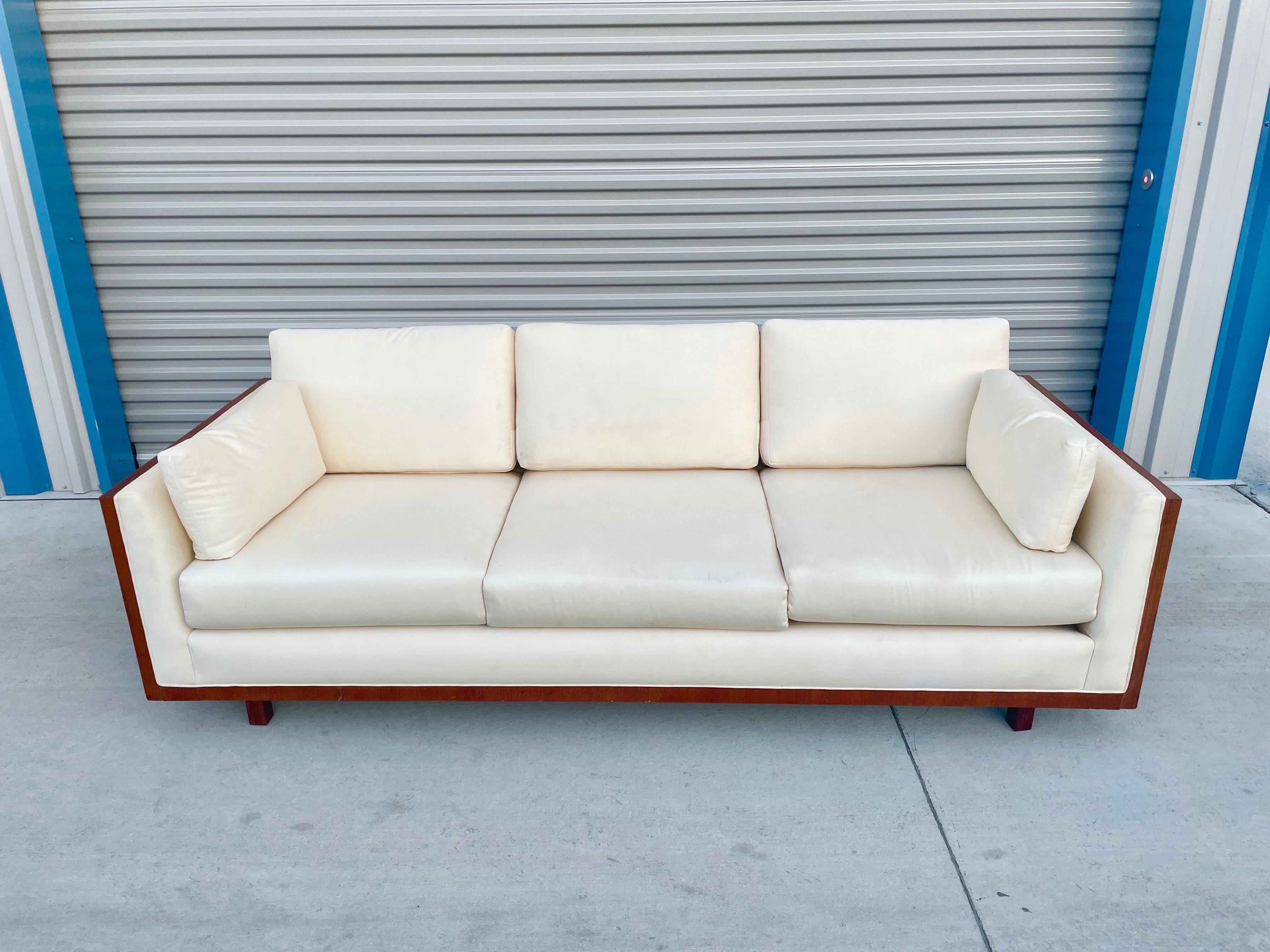 Midcentury teak sofa in the style of Milo Baughman manufactured in the united states, circa the 1960s. This vintage sofa is wrapped in the highest quality teak, giving them an excellent color tone and beautiful grain to the piece. The sofa looks
