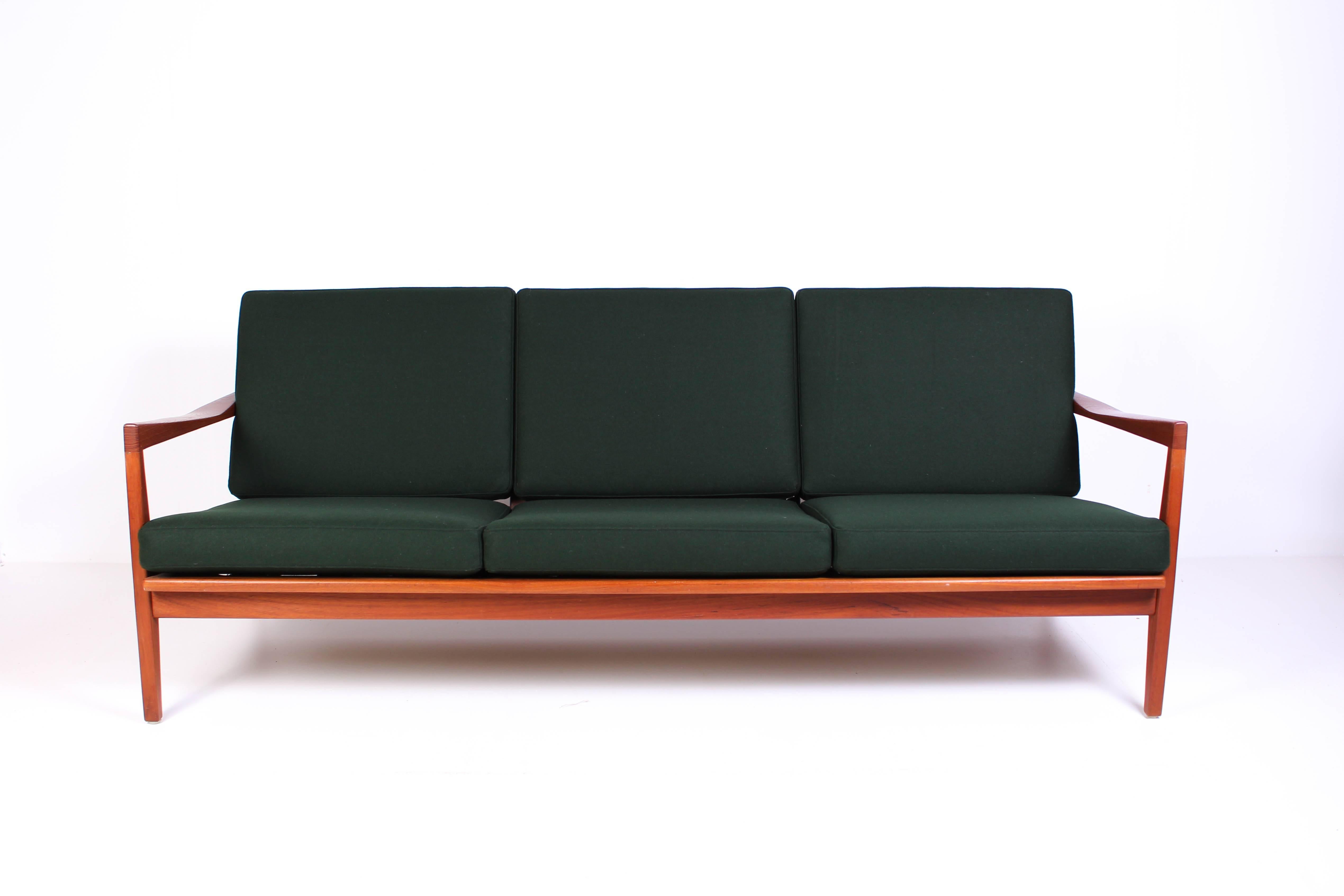 Midcentury Swedish teak sofa by Svante Skogh. This three-seat sofa has new cushions with 100% wool upholstery from Swedish manufacturer Klippan Yllefabrik and nice details such as sculptured backrest and brass fittings.
  