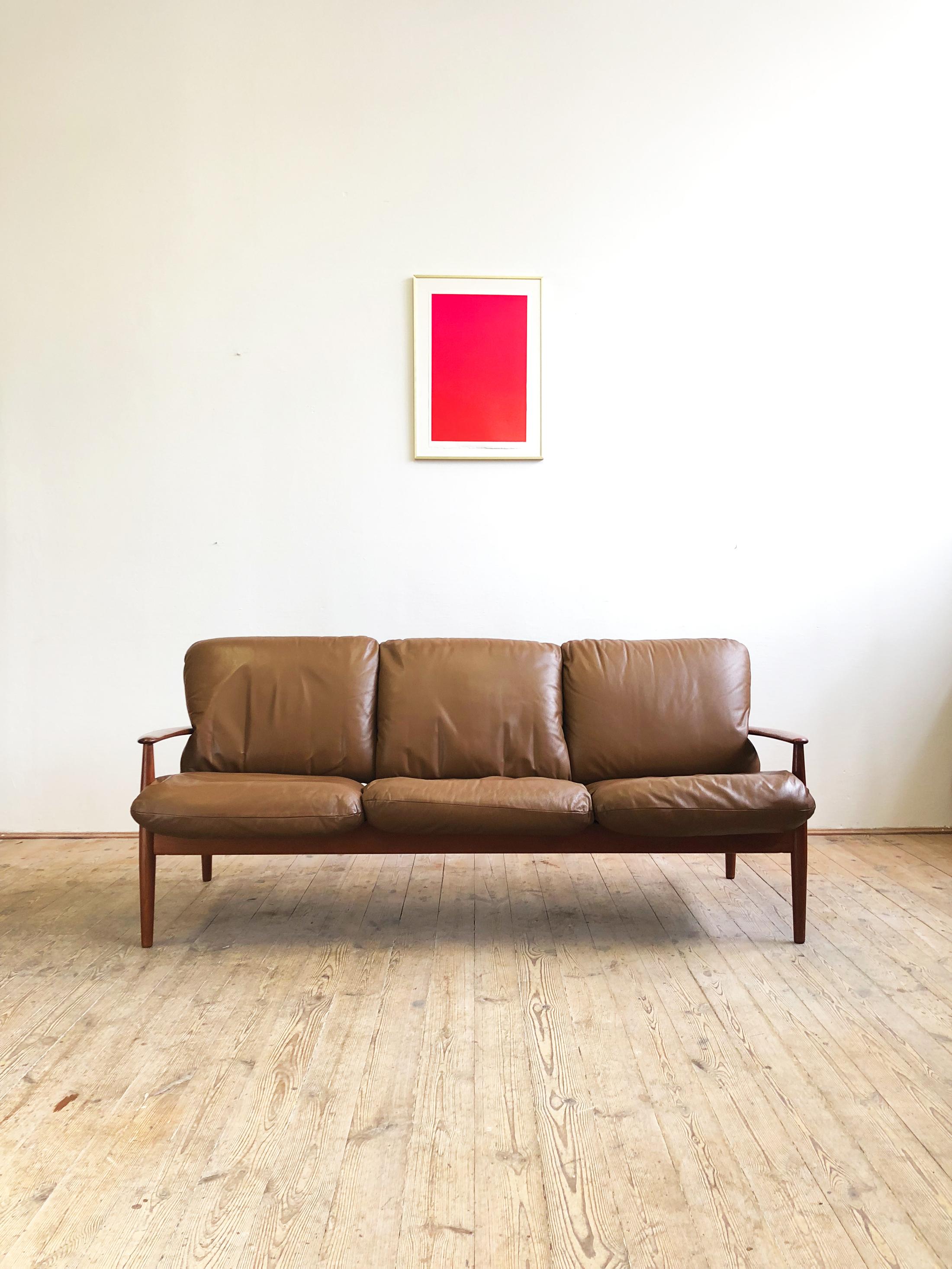 Teak sofa designed by Grete Jalk and produced by Cado. The sofa shows best Danish quality craftsmanship. It comes with soft and very comfortable cushions with a newer soft leather upholstery.