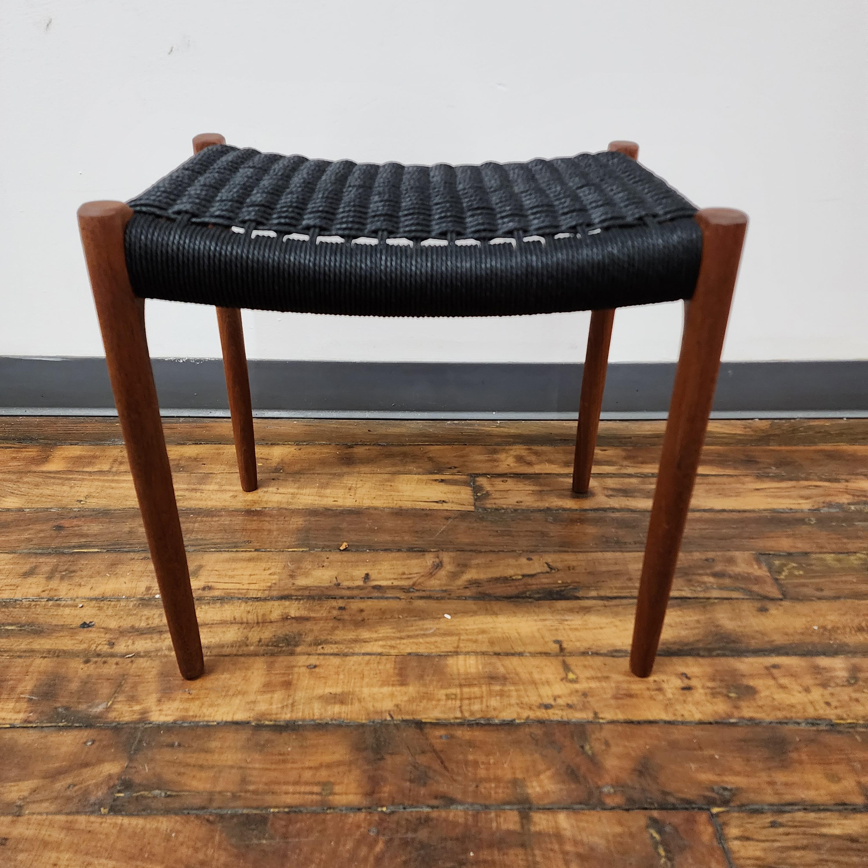 This refinished teak Moller 80A stool with black Danish cord is a stunning example of Scandinavian design at its finest. The teak wood has been expertly refinished to reveal its natural grain and warm, rich tones, creating a sense of organic warmth