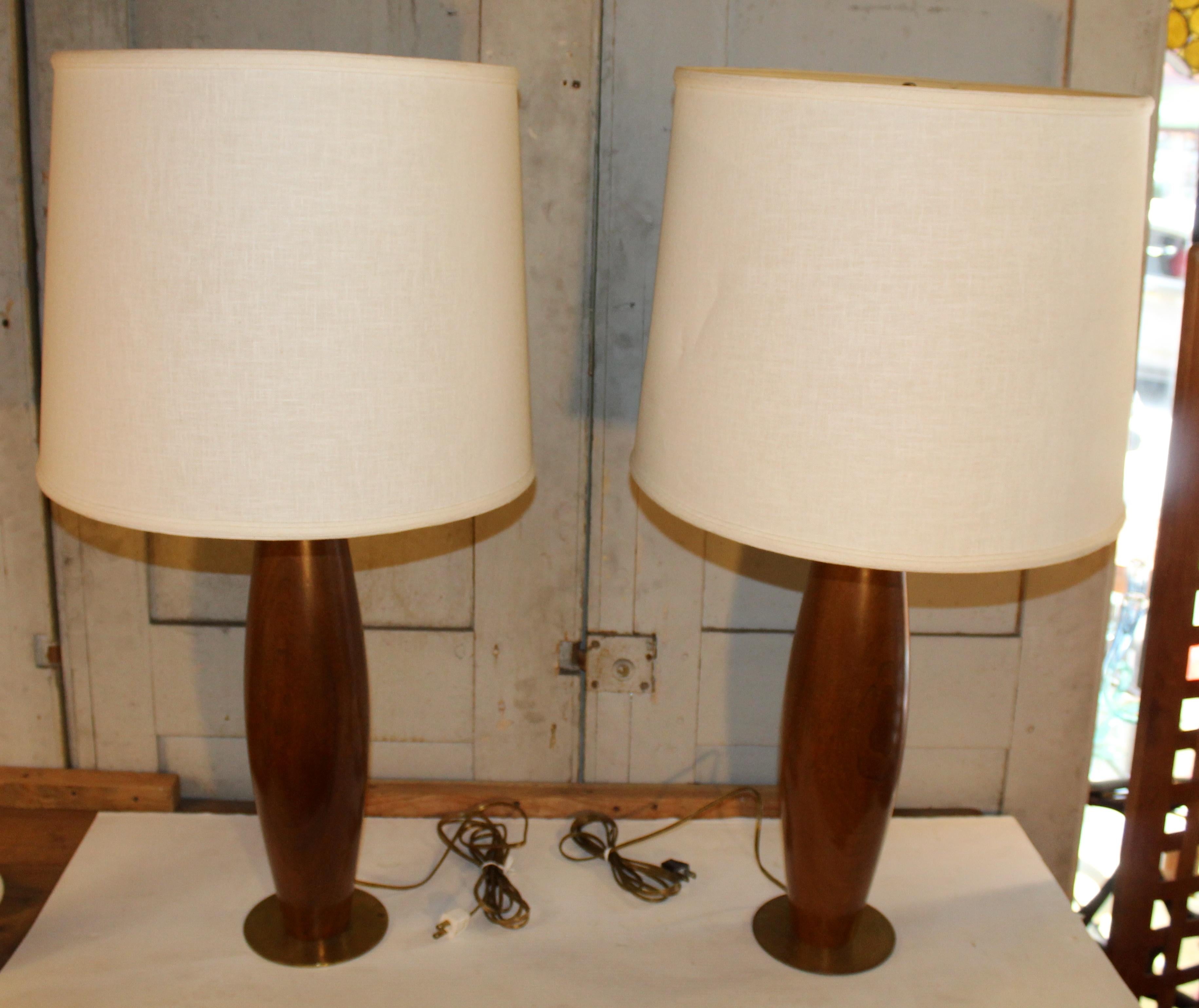 Scultorea ed elegante, questa coppia di lampade da tavolo in stile Mid-Century Modern è caratterizzata da eleganti basi a forma di birillo da bowling realizzate in teak con una ricca venatura. Un classico esempio di design di ispirazione scandinava,