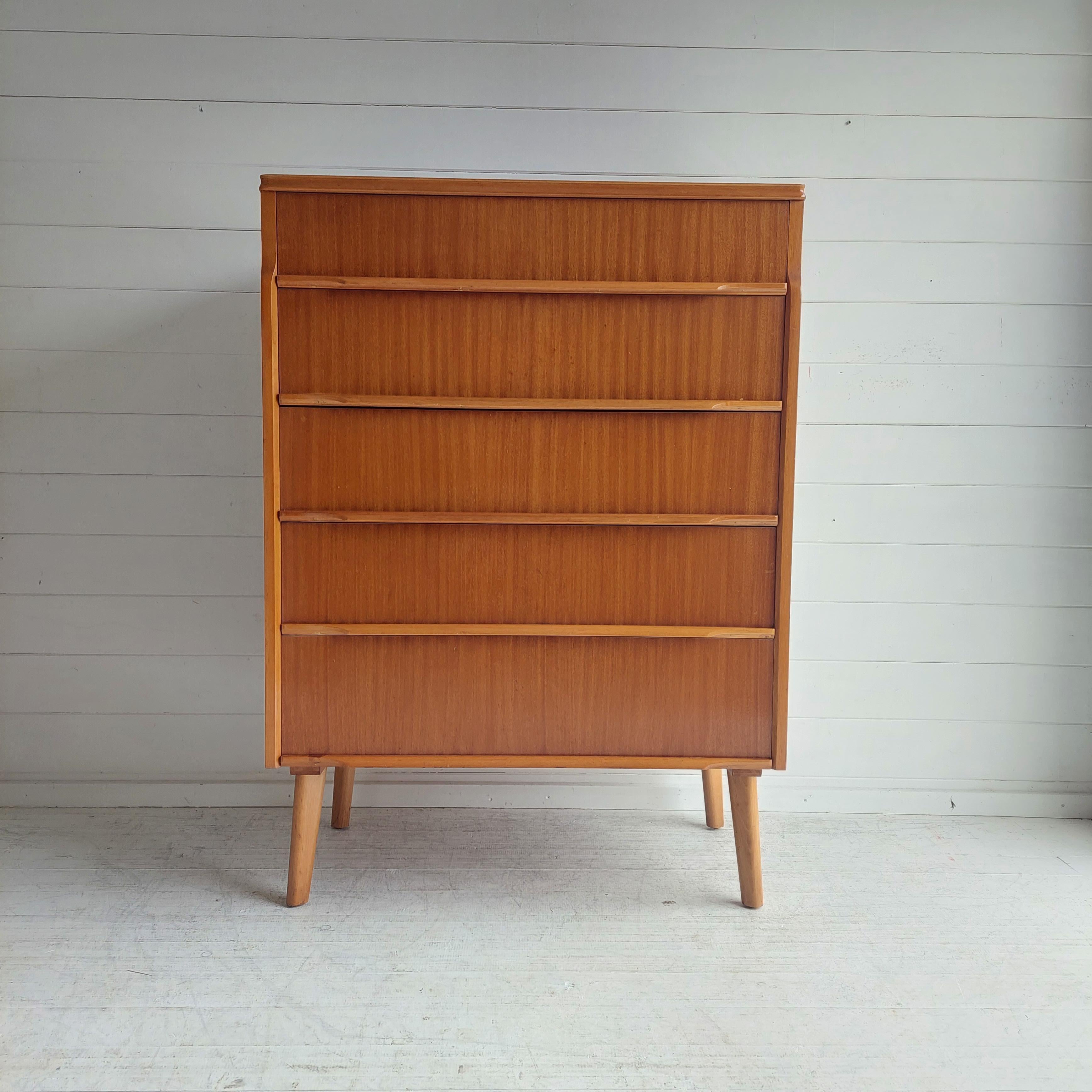 A British tall chest of drawers 
Mid century vintage teak 5 draw chest of drawers Tallboy manufactured by the British company Bluestone and Elvin and this piece is from their Beeanese range.
Circa 1960s

The unit is finished in light teak veneers