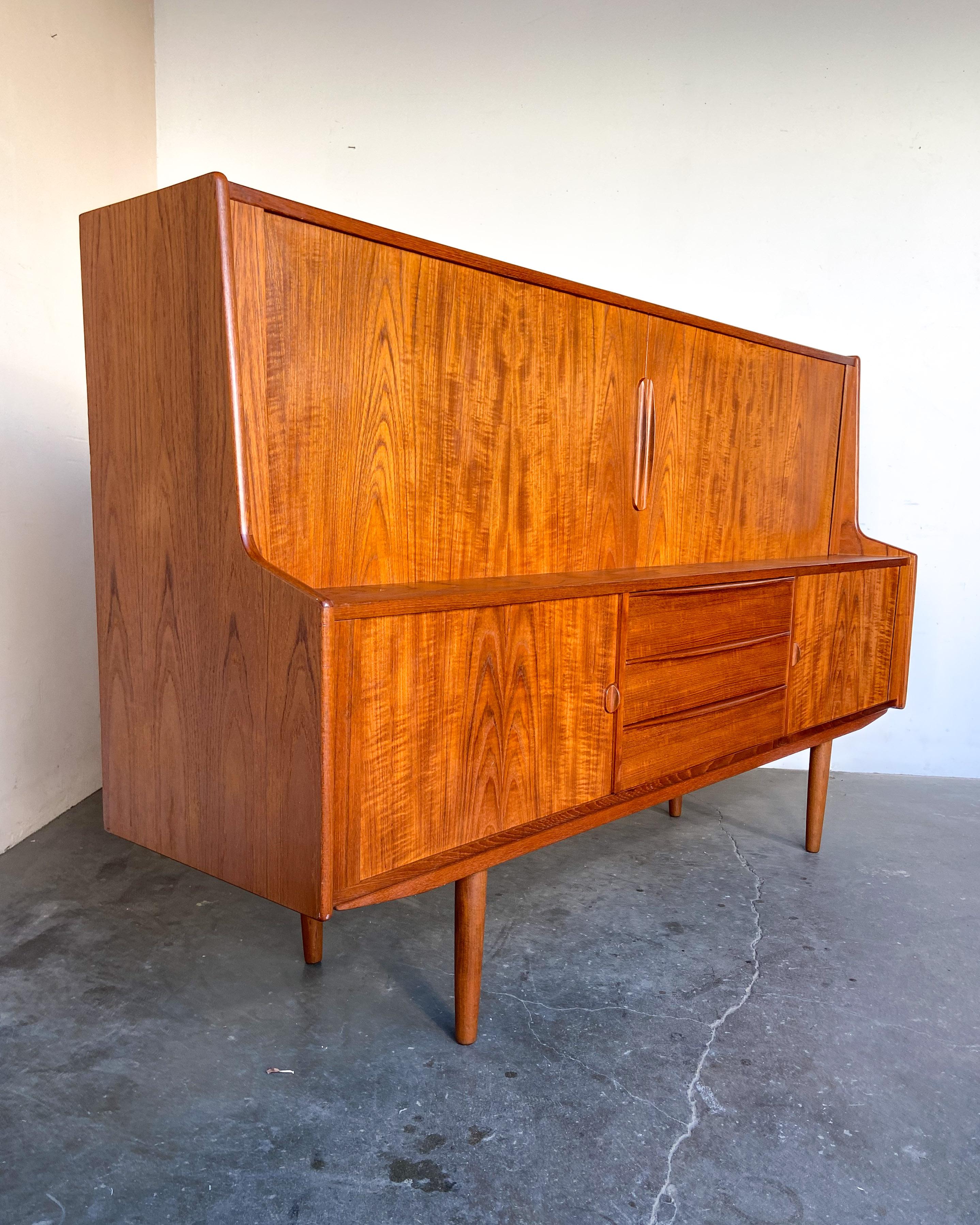 Beautiful teak wood highboard cabinet with sliding tambour doors. Designed by Svend Aage Larsen for Danish Control circa 1960s. Lots of storage with adjustable shelves, shallow emerald felt-lined drawers on top and lower larger drawers. Stunning