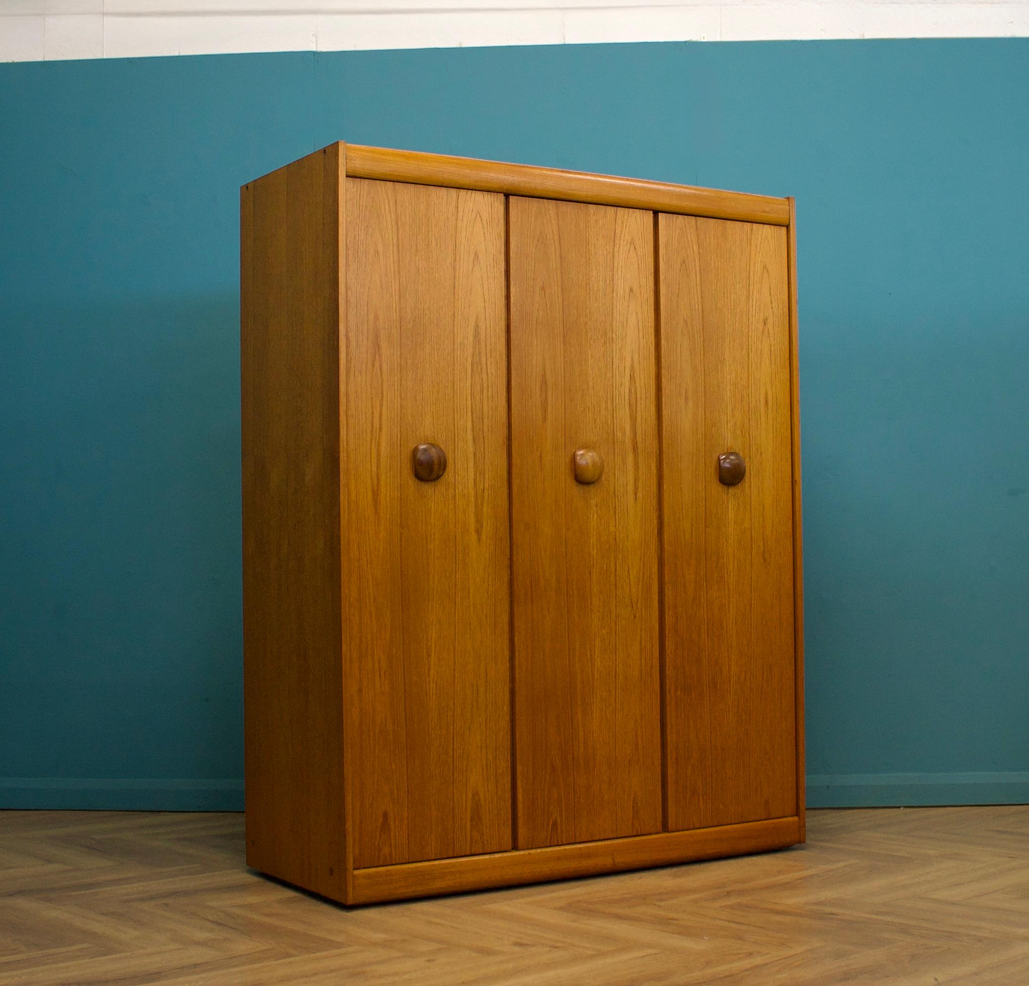 Un armadio freestanding a tre ante in teak da Elliots of Newbury
Realizzato negli anni '60


Dotato di appendiabiti
Lo stile di questo guardaroba è piuttosto minimalista - con le sue linee pulite -.
Caratterizzato da maniglie in legno
